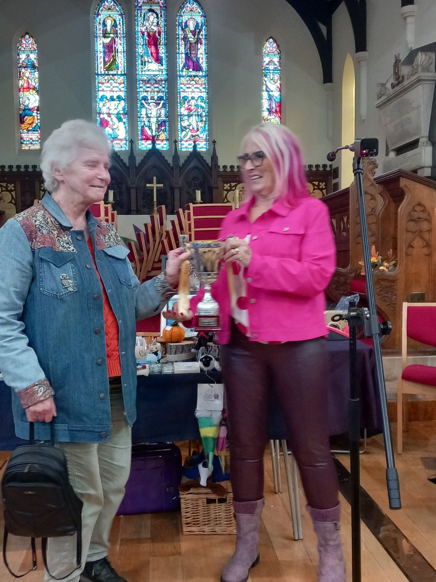 Two women are standing in front of a microphone in a church.