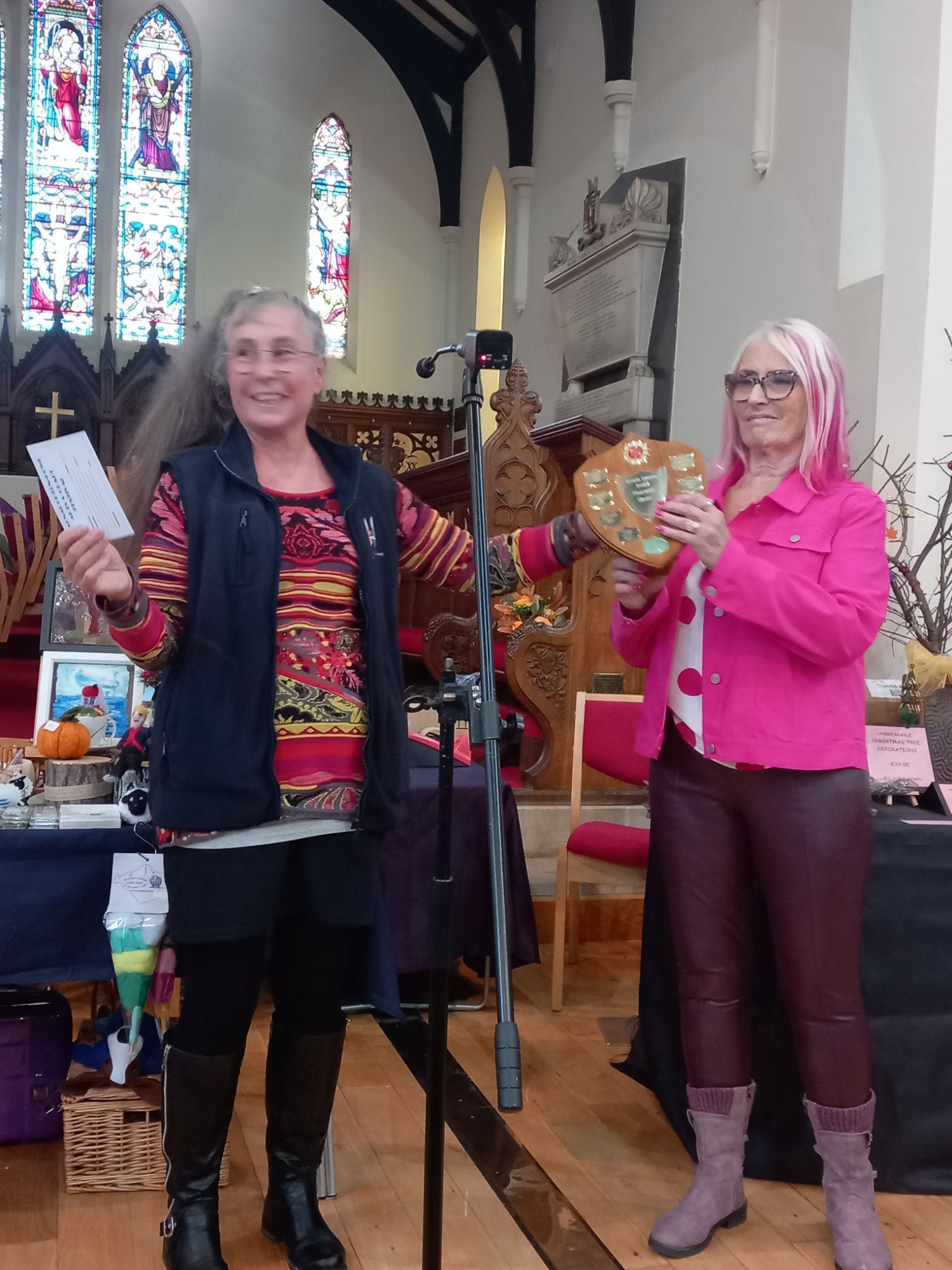 Two women are standing next to each other in a church holding a plaque.