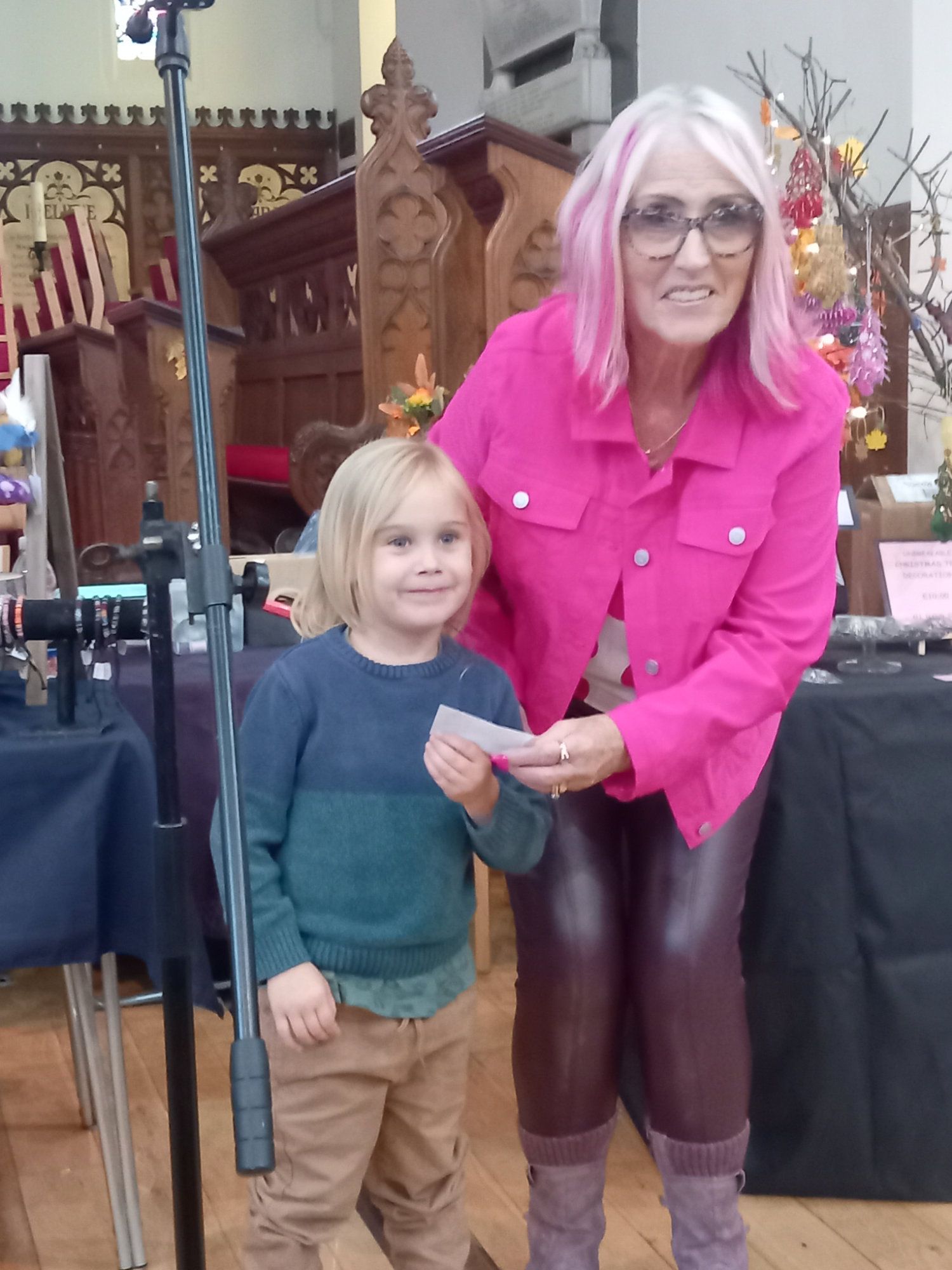 A woman with pink hair is standing next to a little boy.