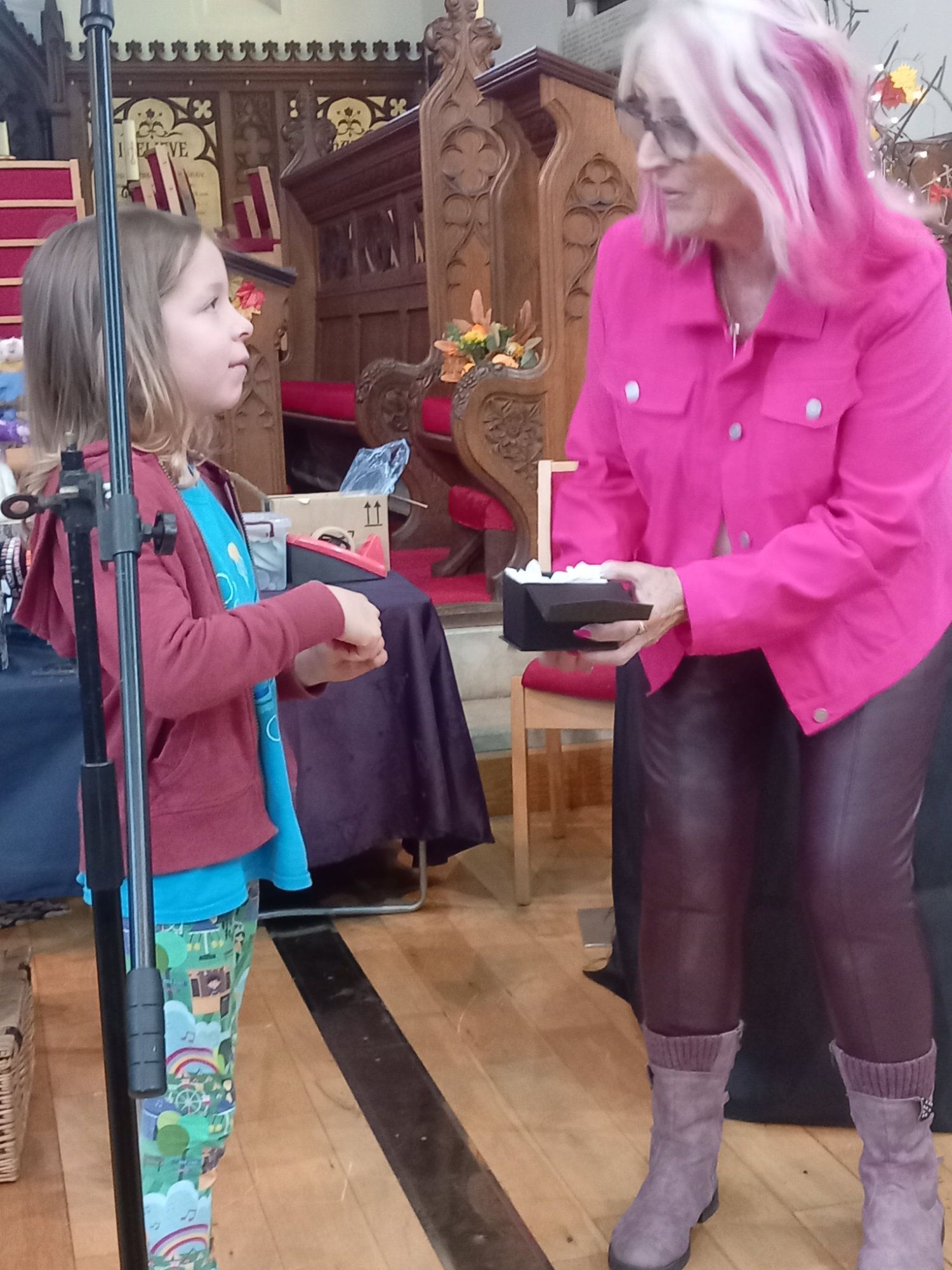 A woman in a pink jacket is talking to a little girl