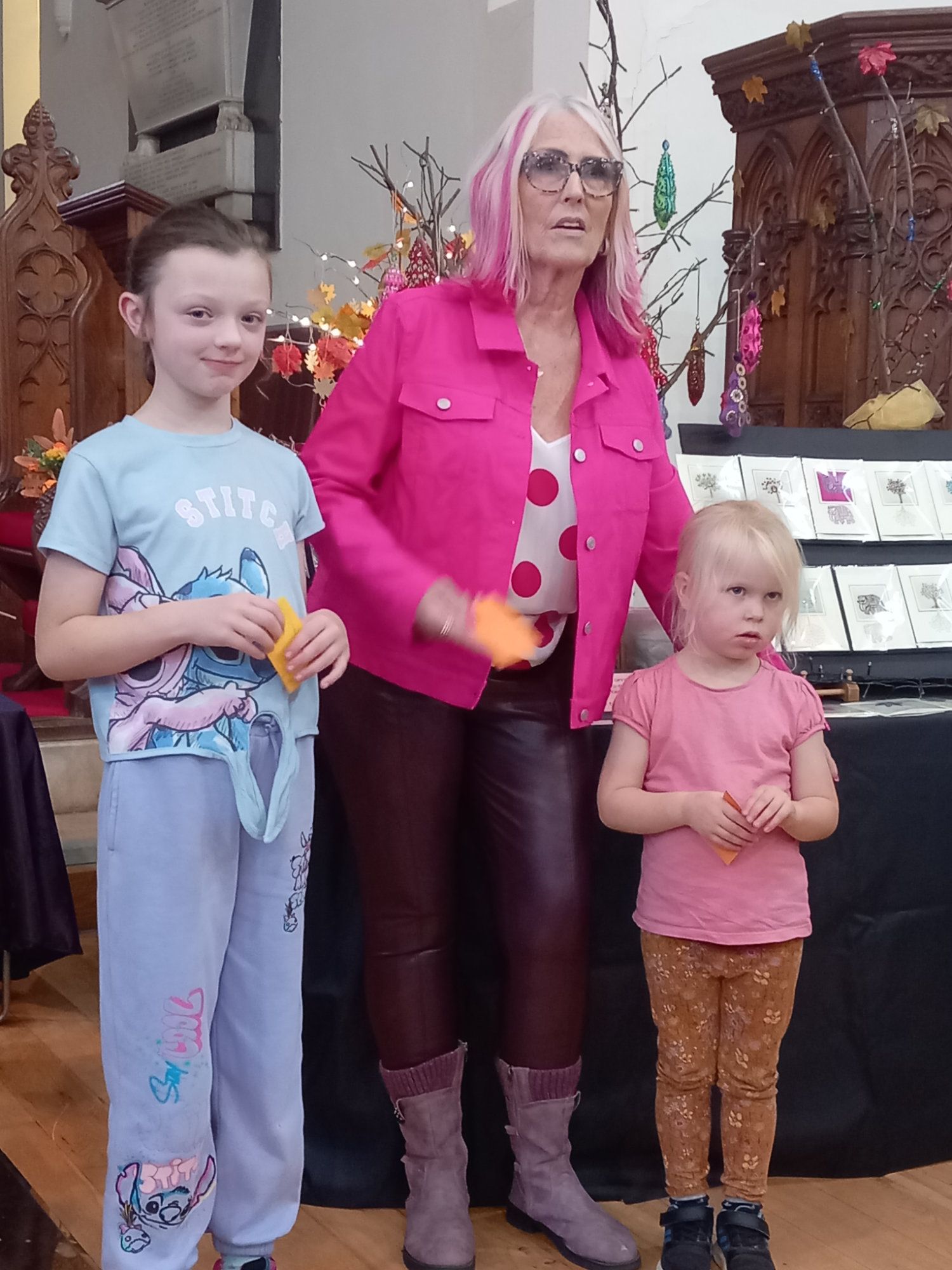 A woman with pink hair is standing next to two little girls