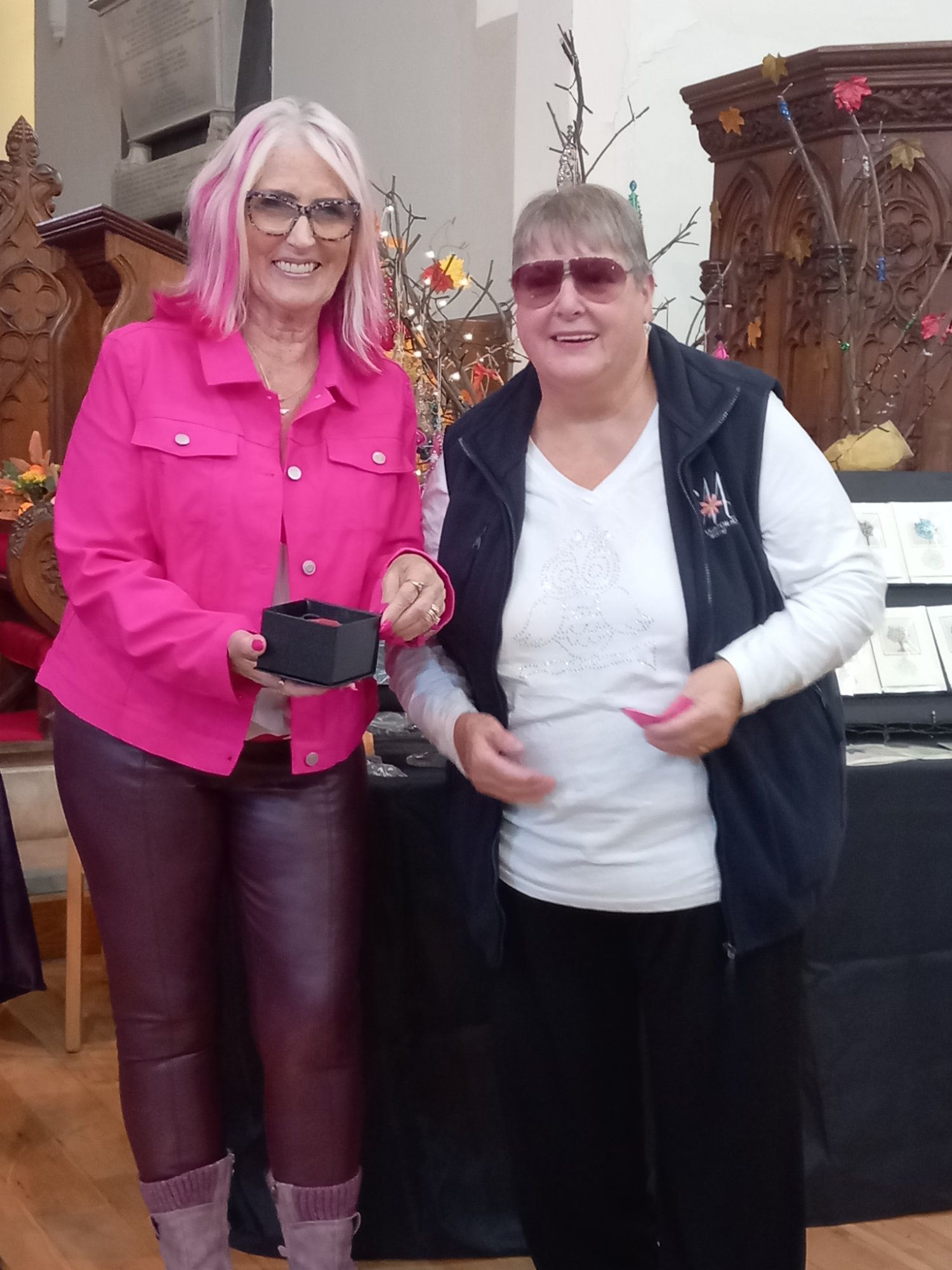 Two women are standing next to each other and one has pink hair