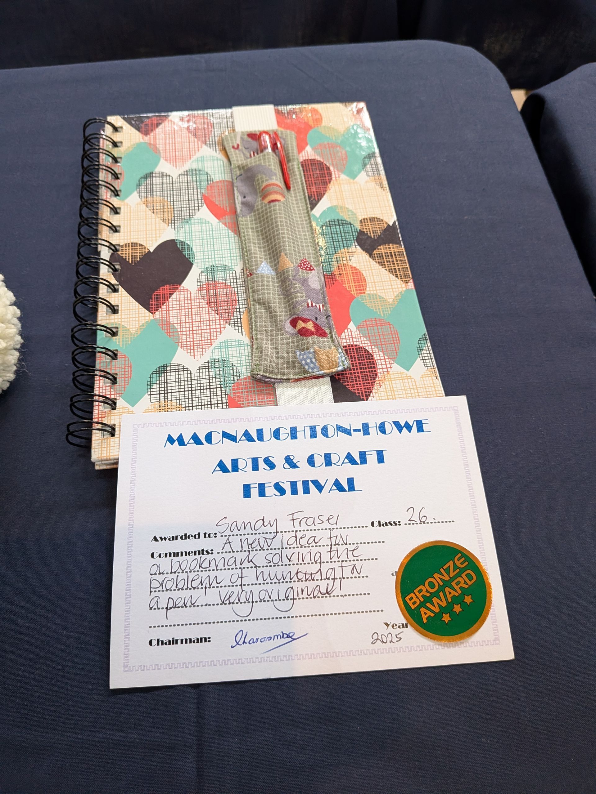 Notebook, pens, and festival pass on a blue surface.