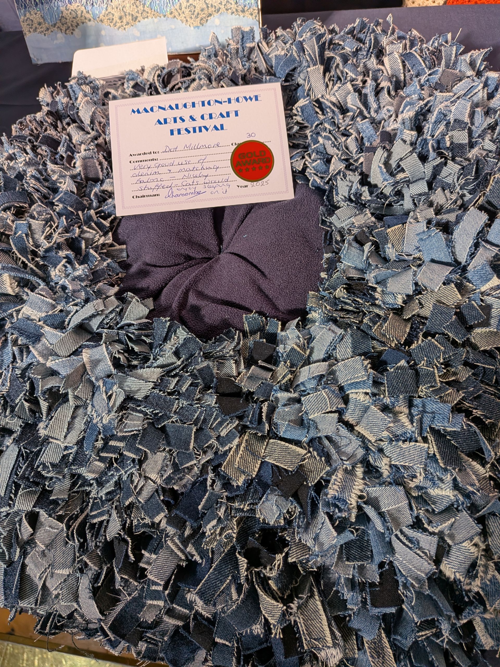 Denim rag rug with dark center and a handwritten note attached.