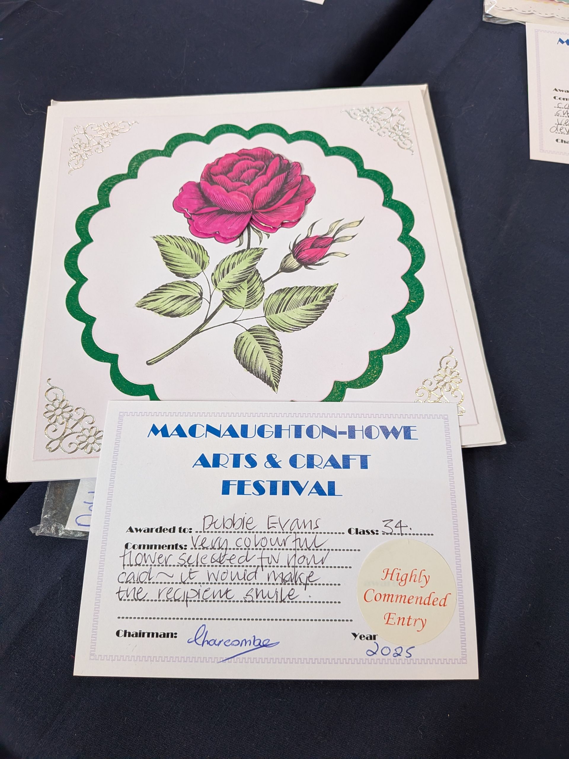 A framed rose drawing with a festival award in front.
