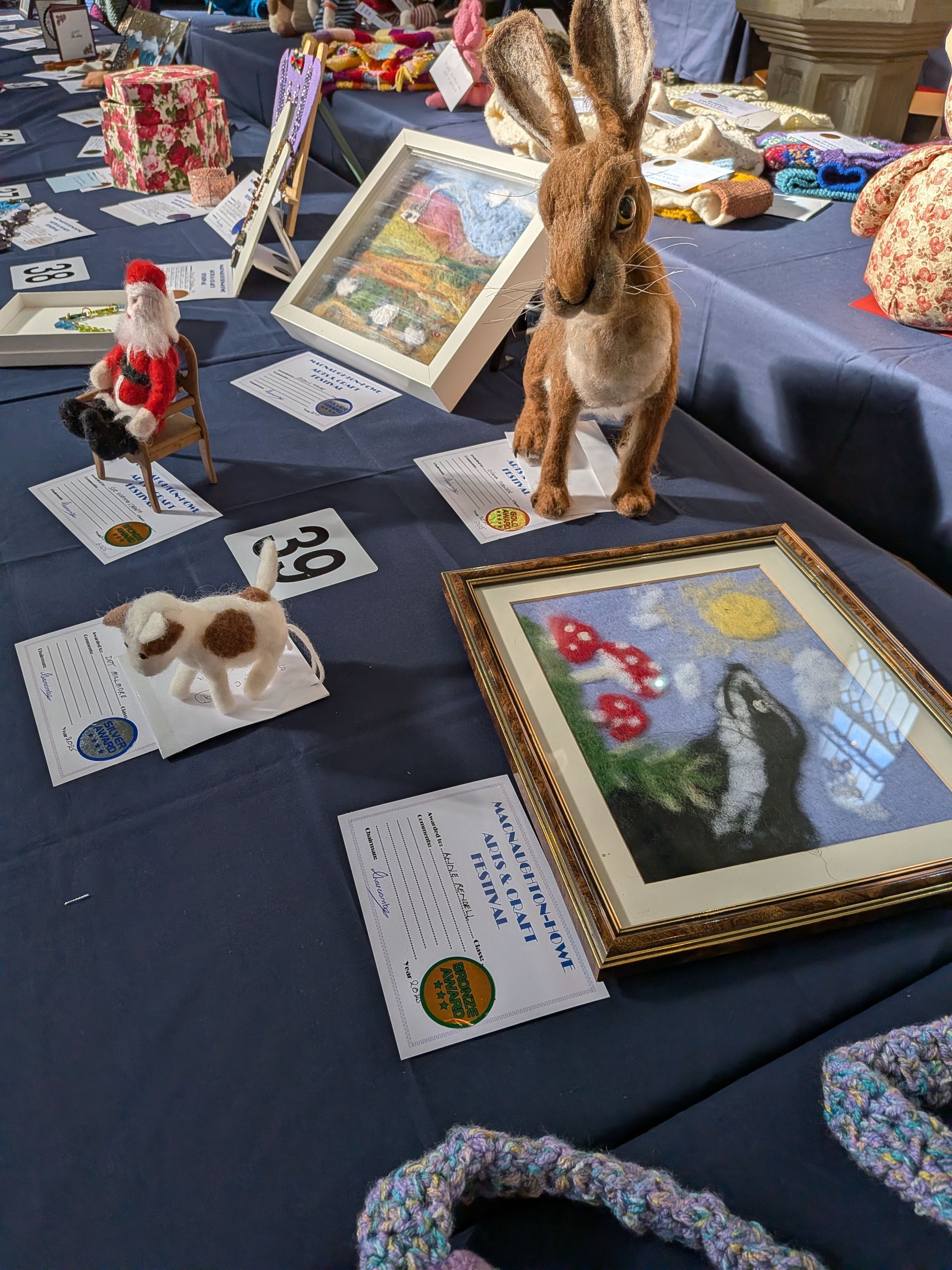 A display table with craft items, including a rabbit figurine, framed art, and a small dog.