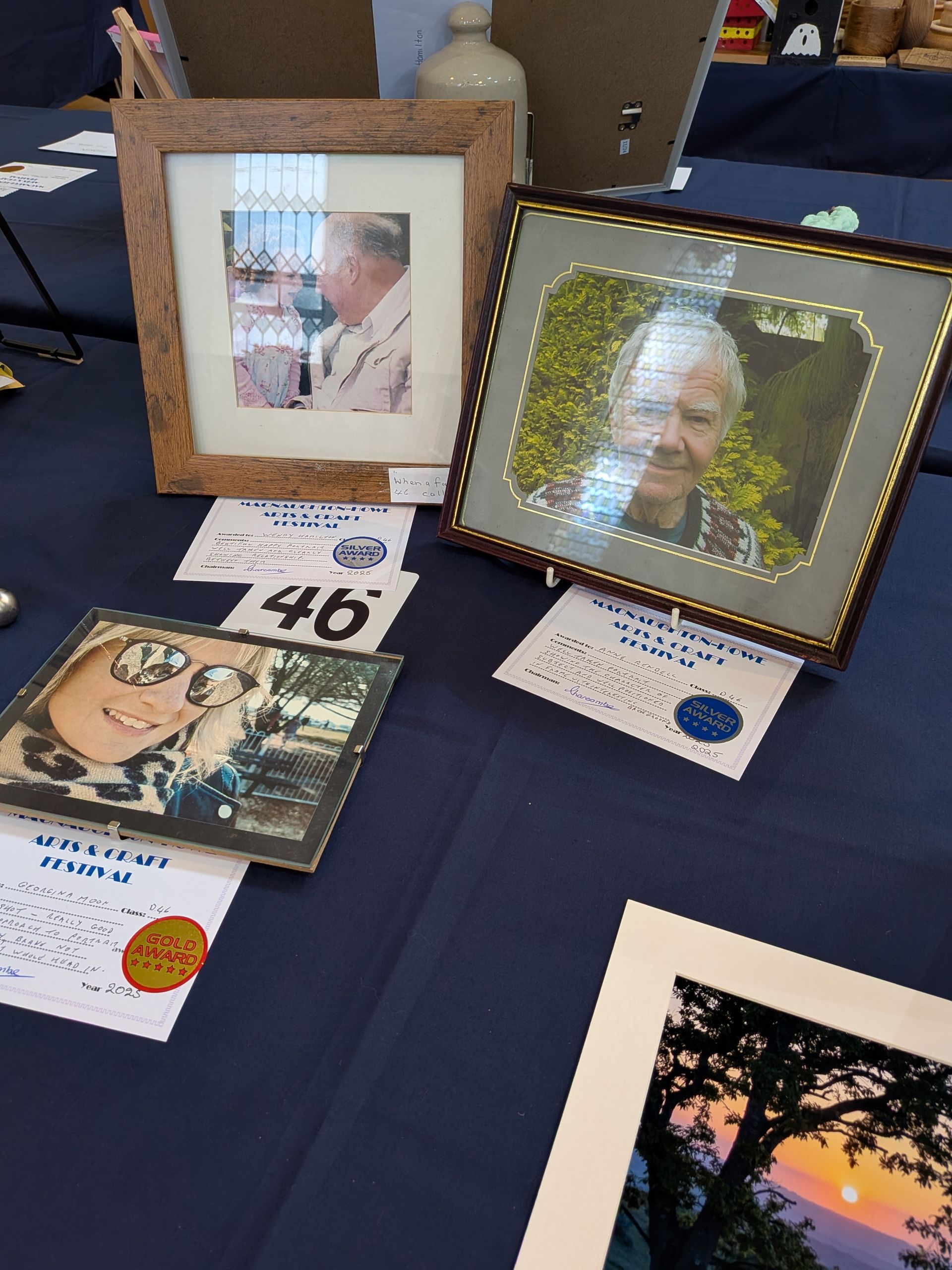 Photos in frames displayed on a table. One is a portrait, others show outdoor scenes.