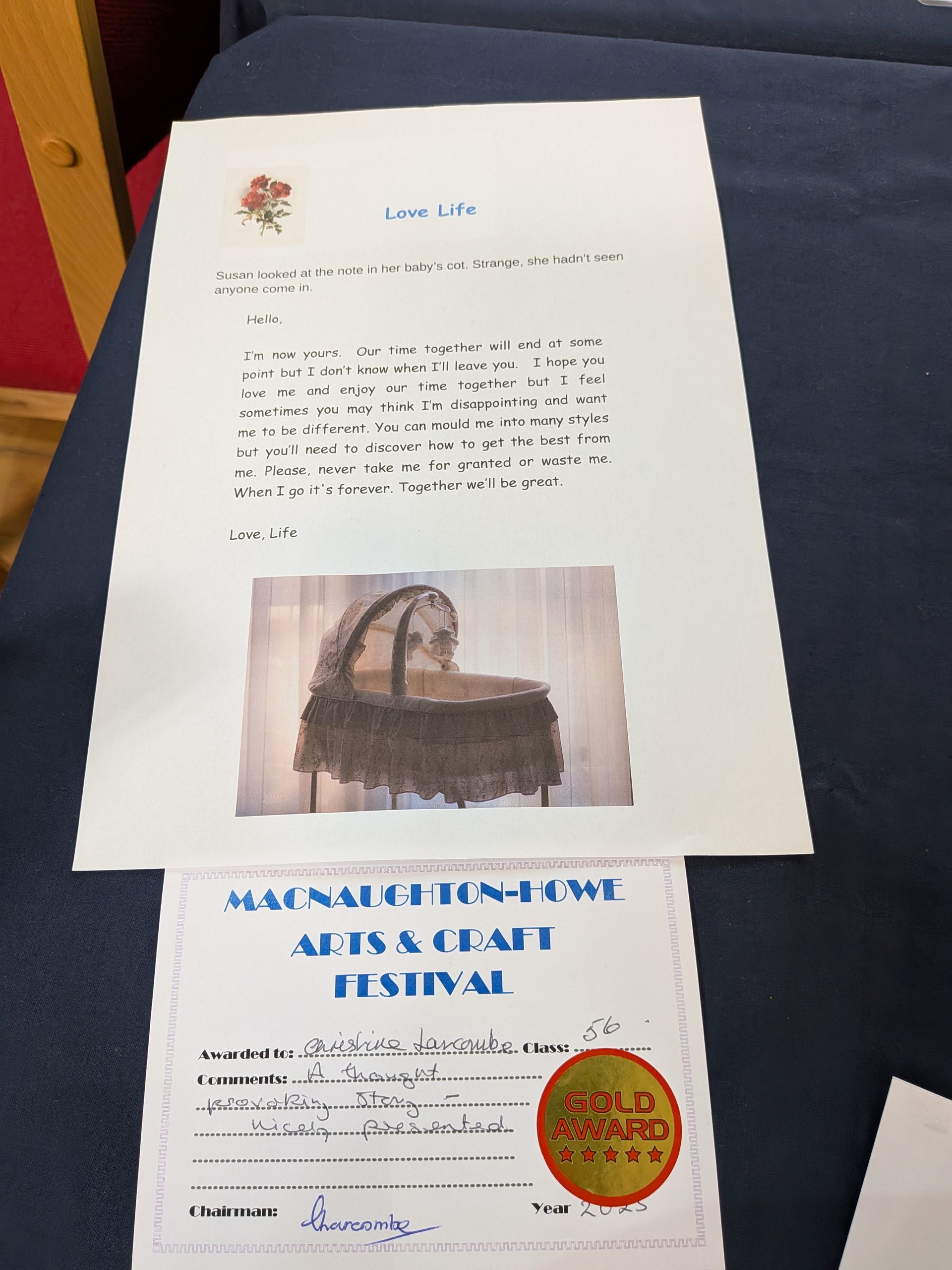 A letter and a festival certificate sit on a dark surface. The letter has a floral symbol and photo of a woven basket.