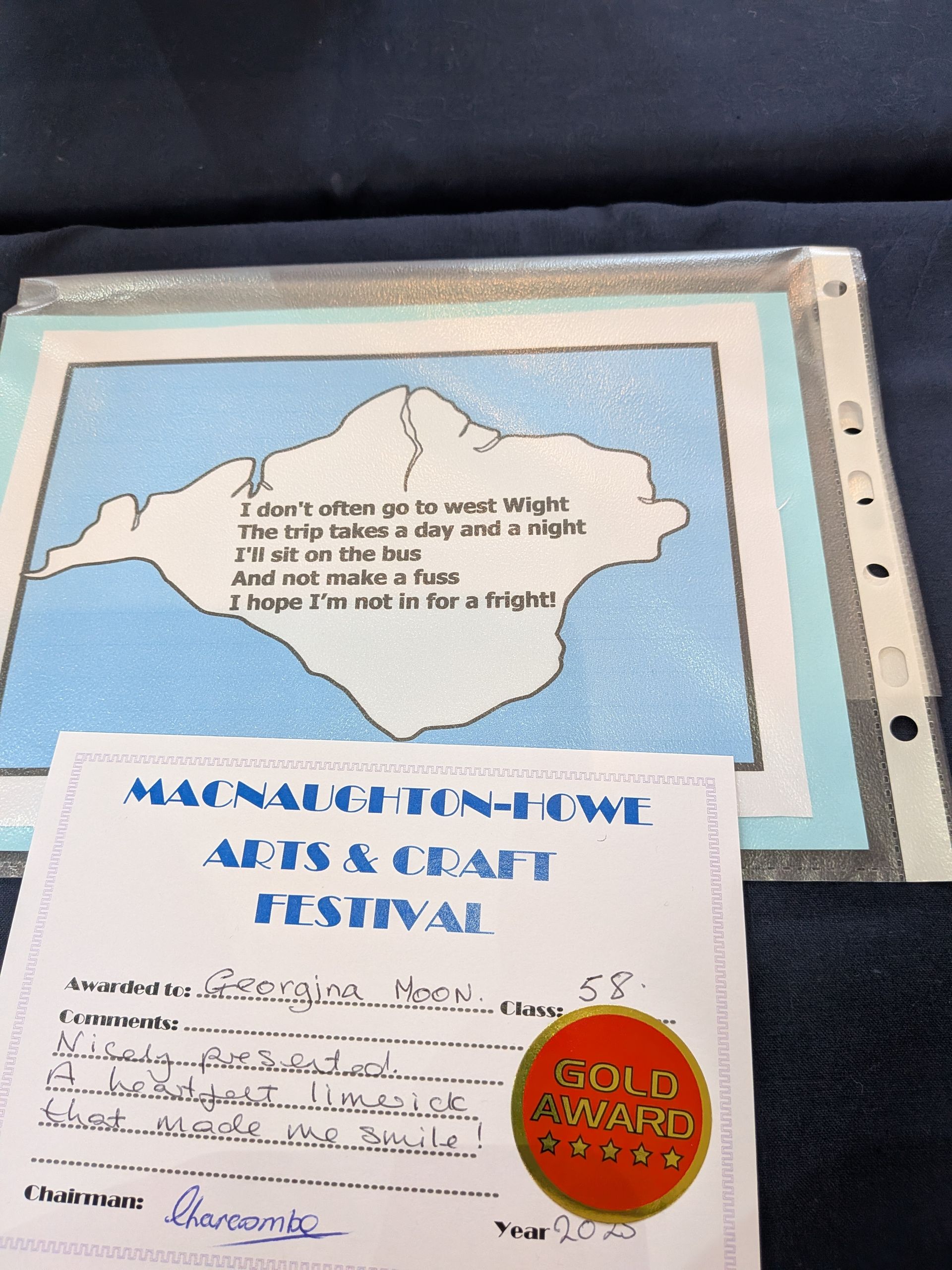 A framed art piece with poem about an island, and a Gold Award certificate from a craft festival.