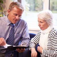 Man in a tie reviewing papers with elderly woman