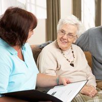 Elderly woman looking at a caregiver with an open folder