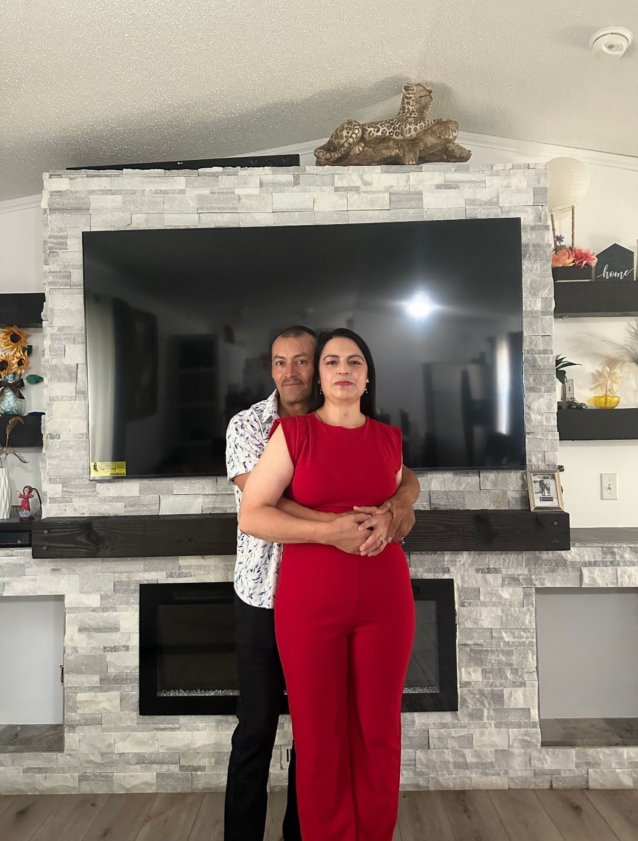 A man and a woman are standing in front of a television in a living room.