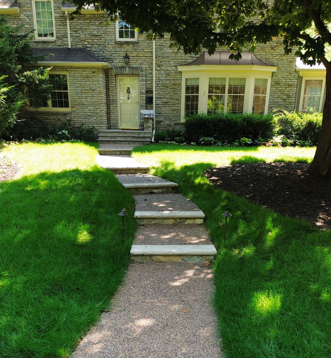 Stone house with a gravel path, steps, and green lawn leading to the front door.