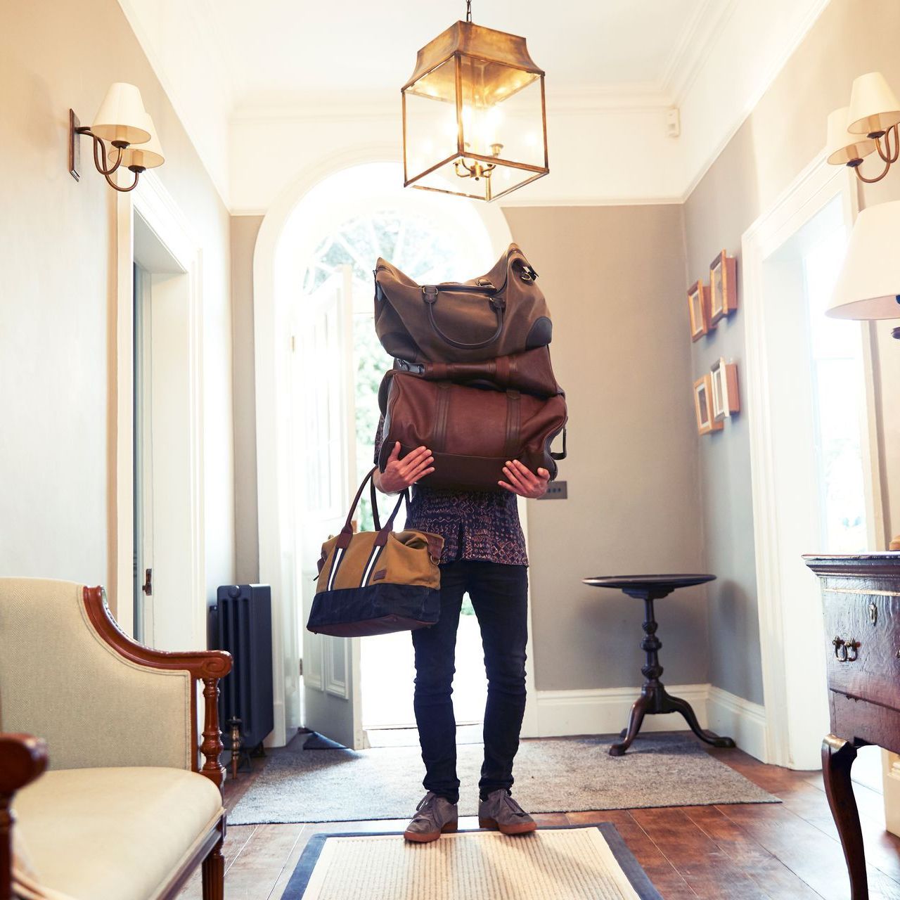A man carrying a stack of bags in a hallway
