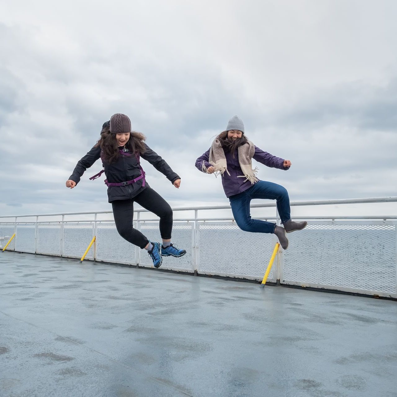 Two people are jumping in the air on a boat