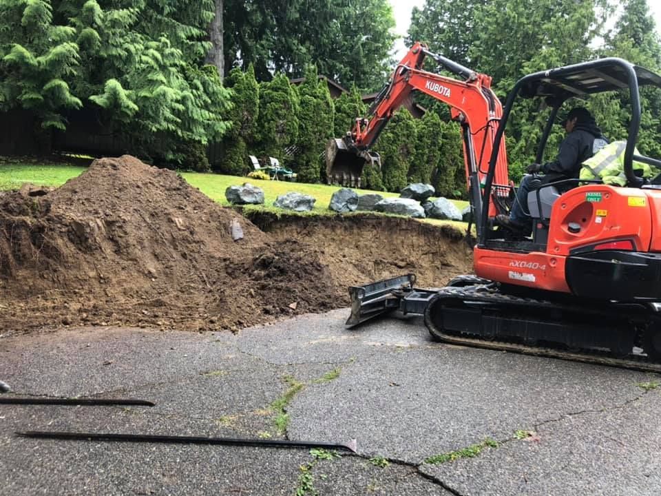 Man is driving an Excavator on a Dirt Road - Bellingham, WA - Garden of Eden Landscape LLC