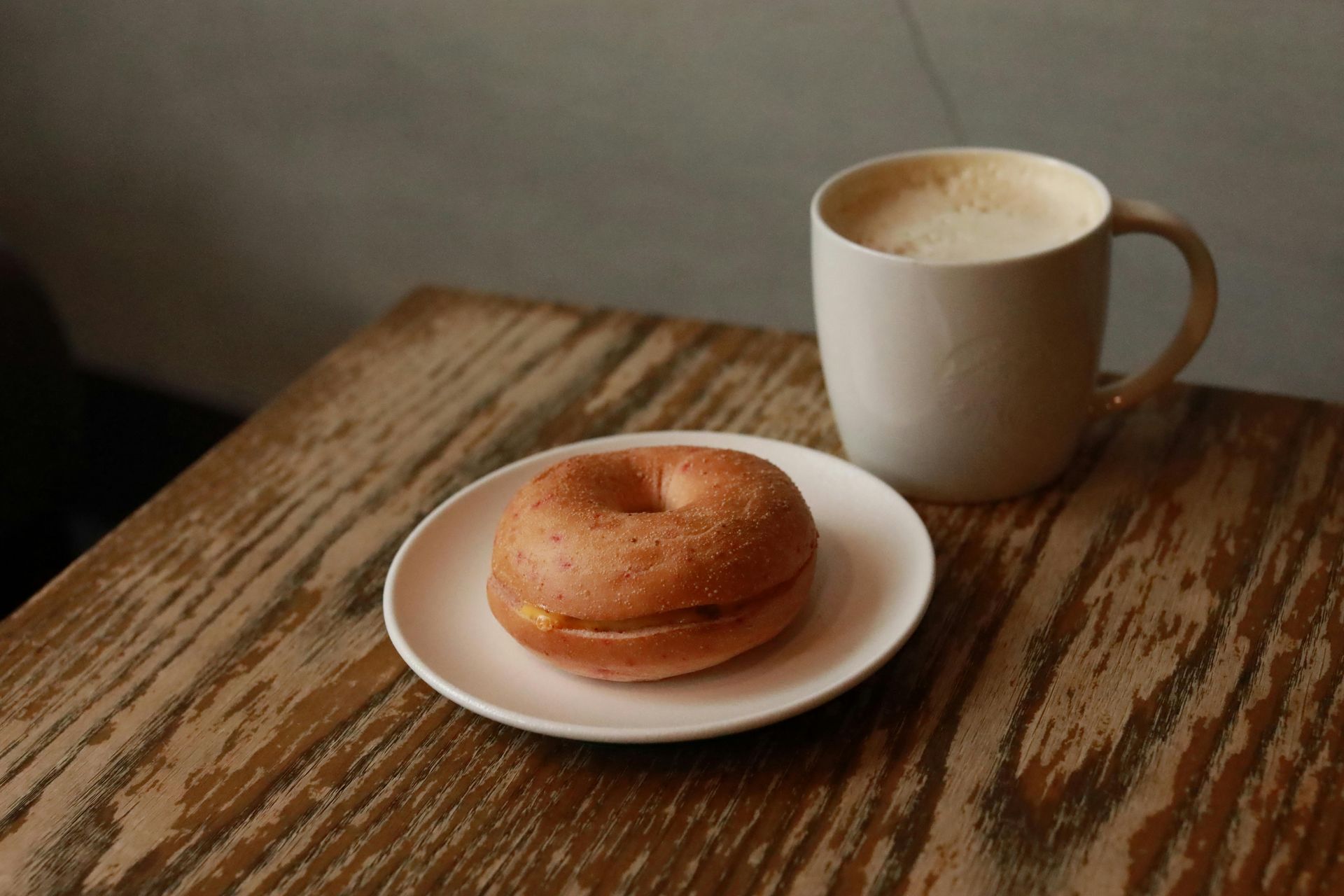 A bagel next to a cup of coffee.