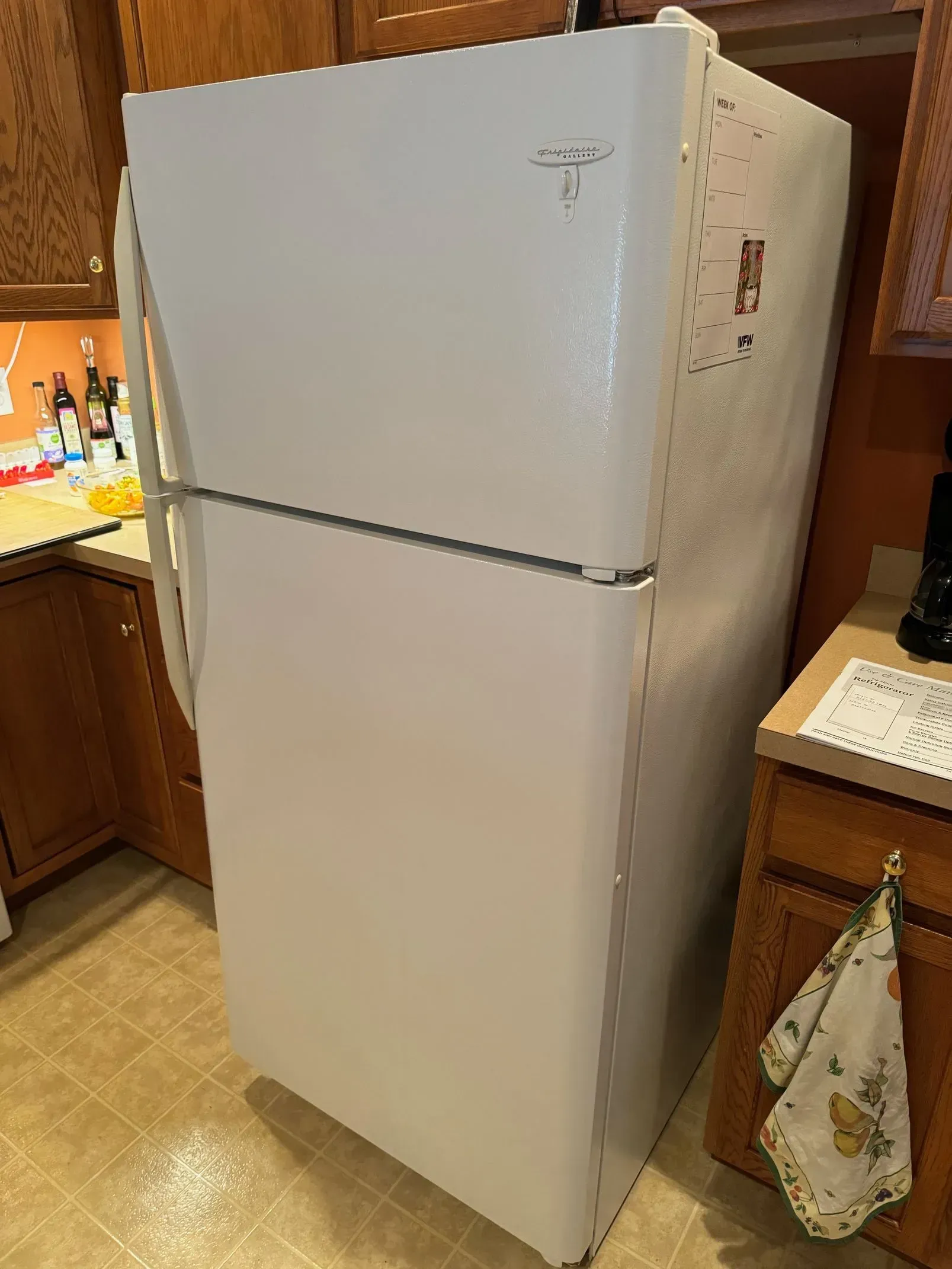 A white refrigerator is sitting in a kitchen next to a counter.