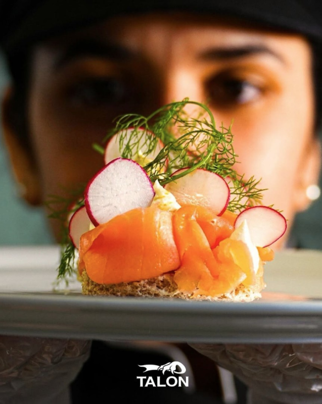 Lo chef presenta un antipasto di salmone con ravanelli e aneto su un piatto.