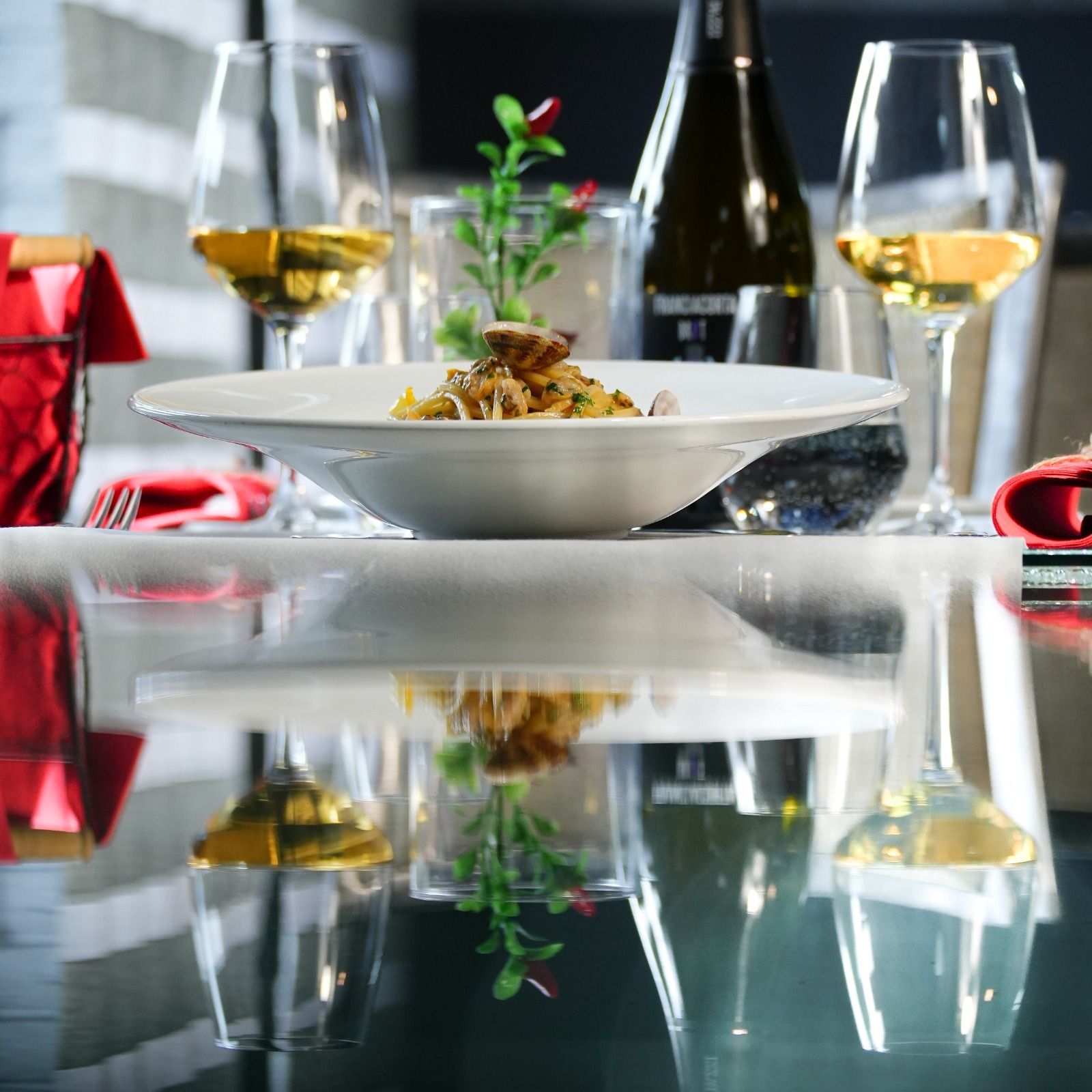 Elegante apparecchiatura da tavola con una ciotola bianca di cibo, bicchieri da vino e una bottiglia di vino.