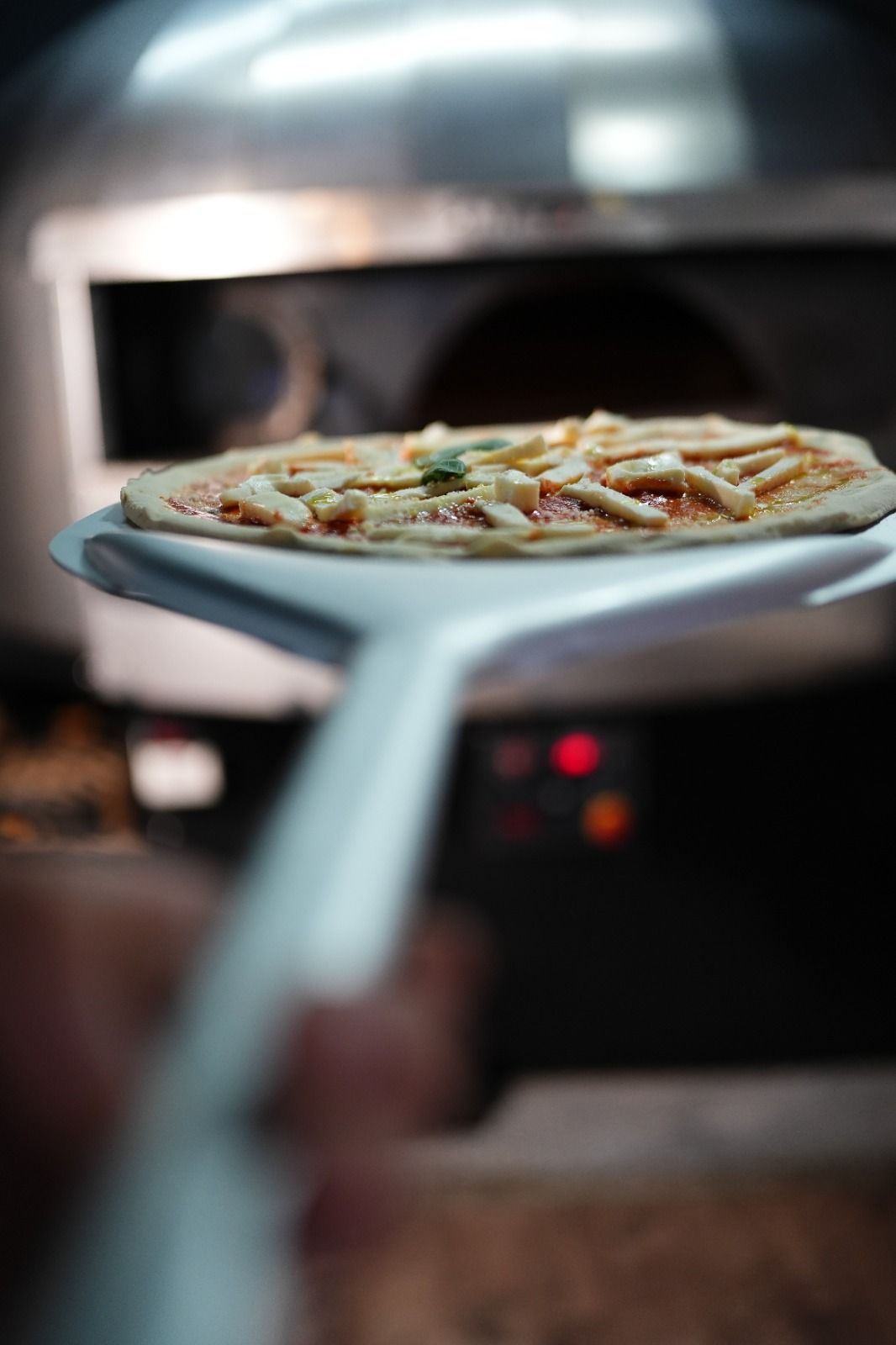 Pizza su una pala inserita nel forno per pizza.