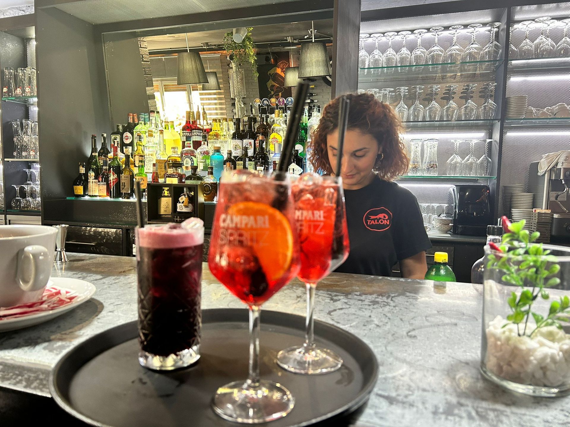 Cocktail su un vassoio da bar. Un barista sorride dietro il bancone.