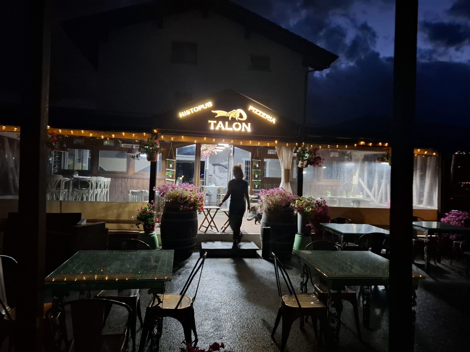 Un ristorante di notte con una persona in piedi sulla soglia. L'insegna 