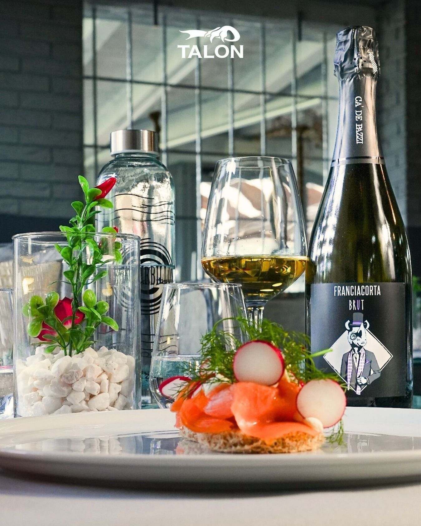 Un piatto con salmone e ravanelli, una bottiglia di champagne e bicchieri d'acqua su un tavolo.