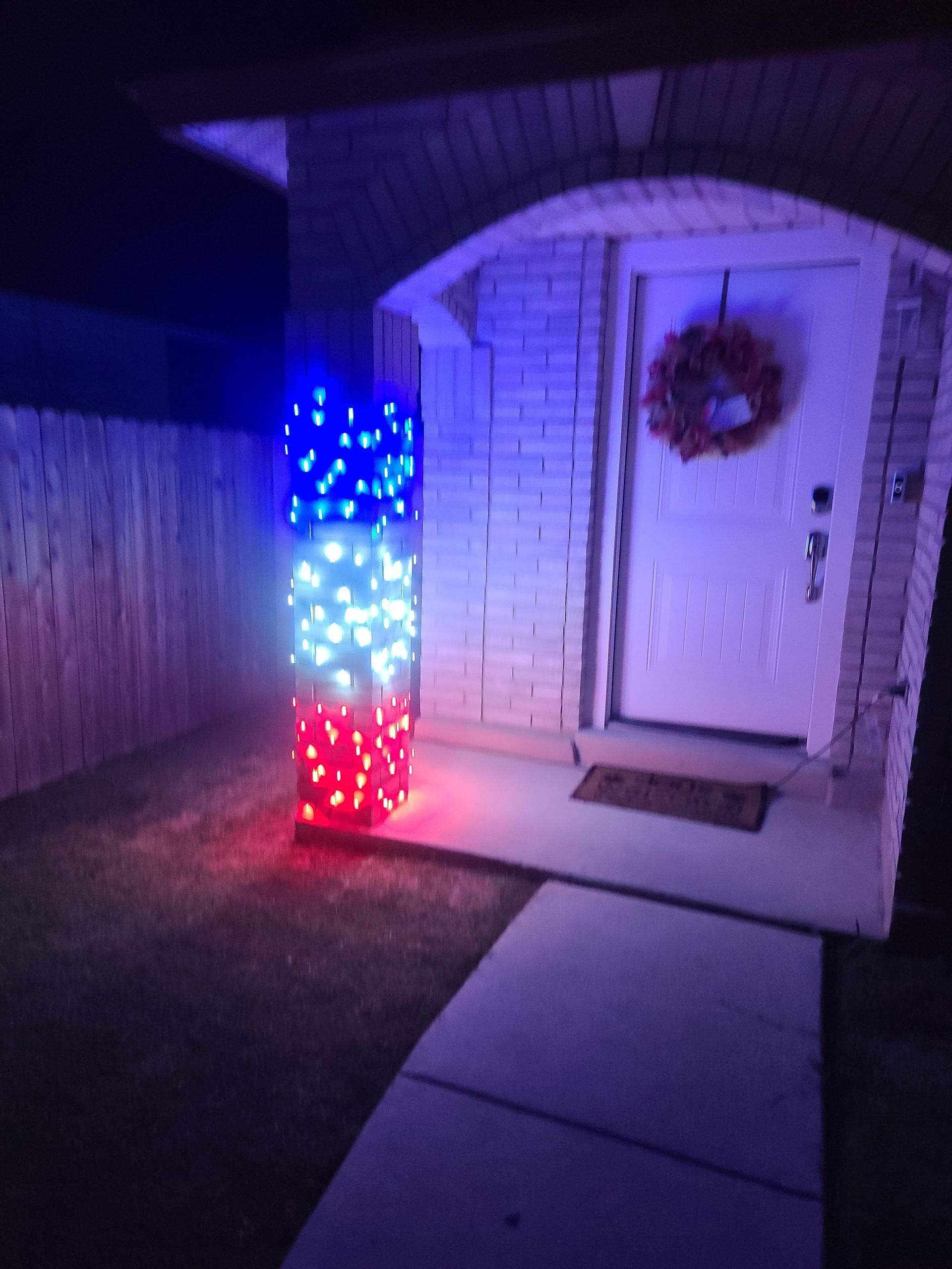 Red, white, and blue lights on pillar; front door with wreath.