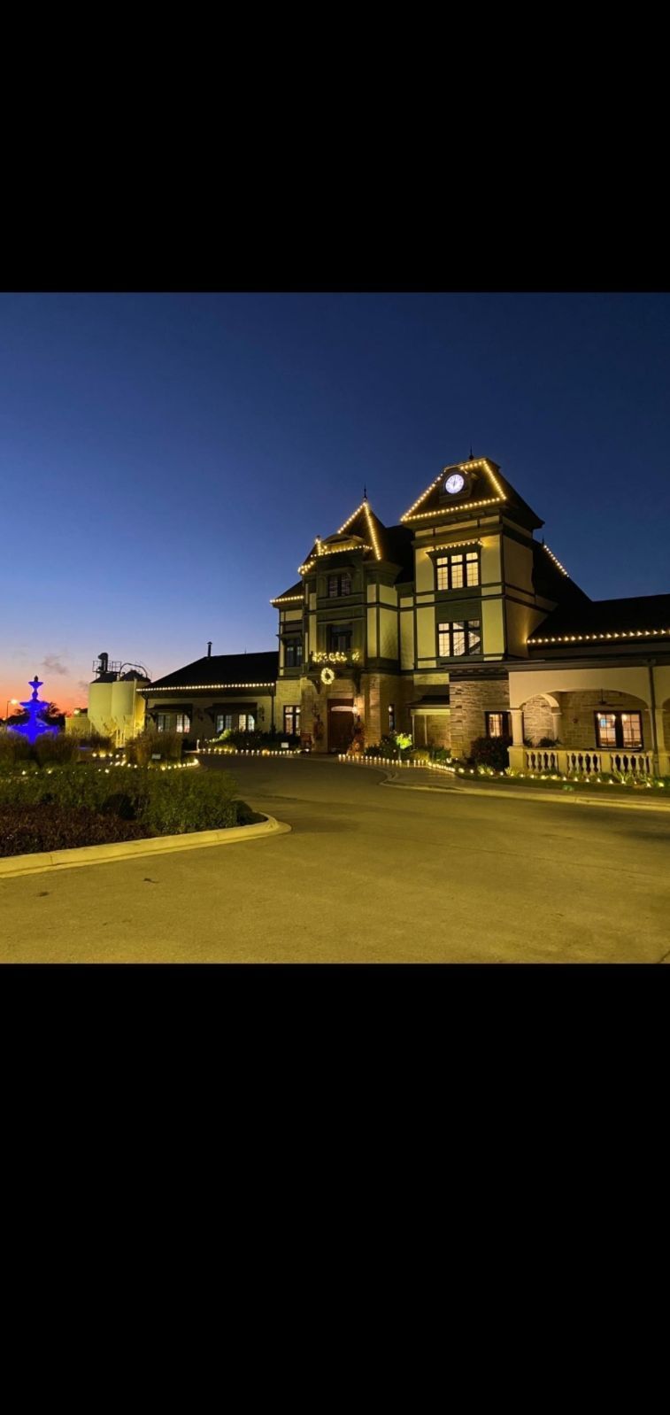 A large historic building lit up at dusk. The sky is a gradient of blue and orange.