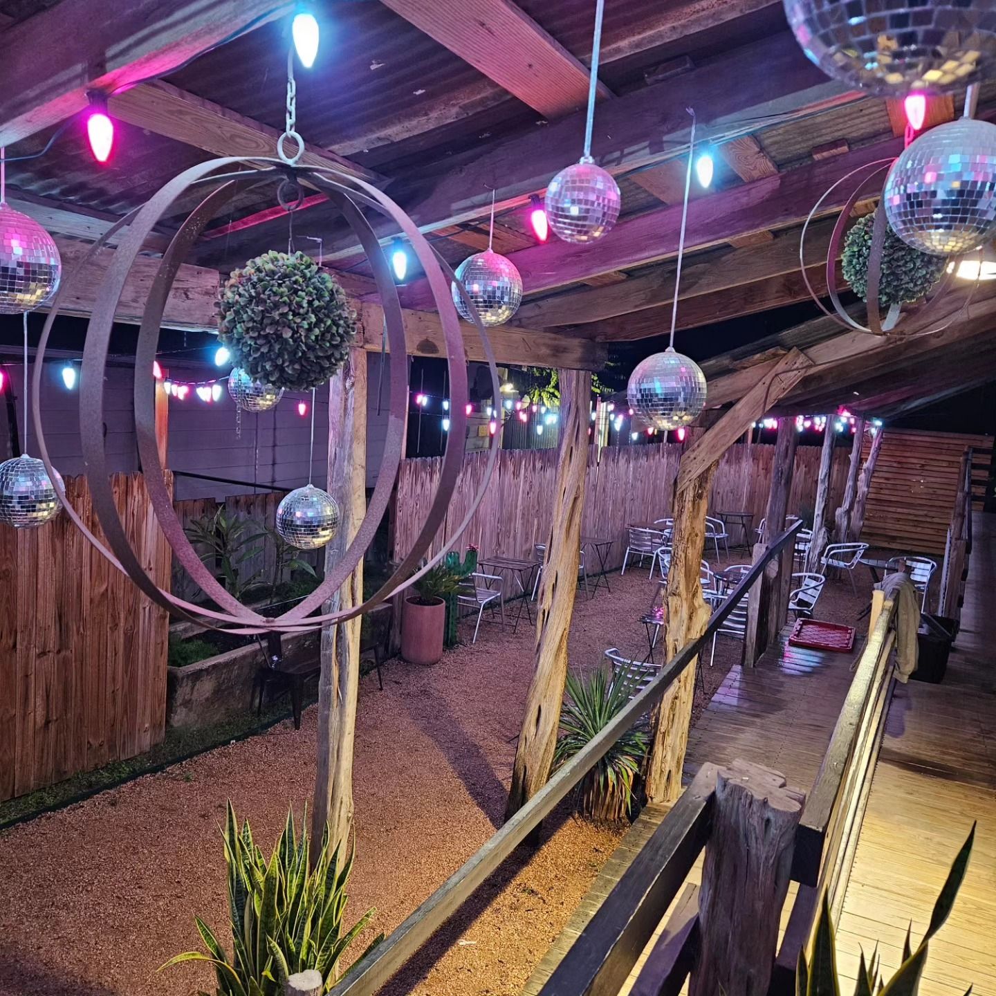 Outdoor party space with disco balls, string lights, and a wooden railing.