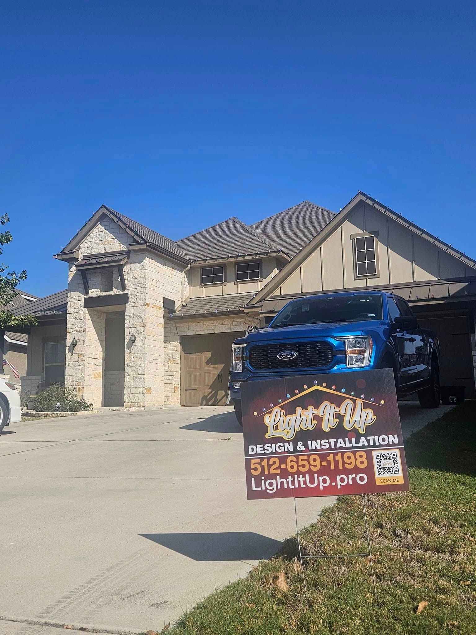 Blue truck in front of a house with a sign for LightUp.pro; sunny day.