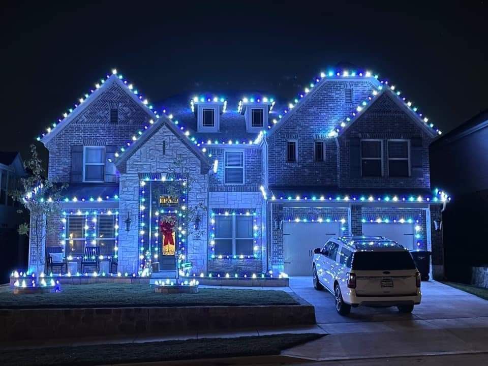 House decorated with blue Christmas lights, driveway, and parked white van.