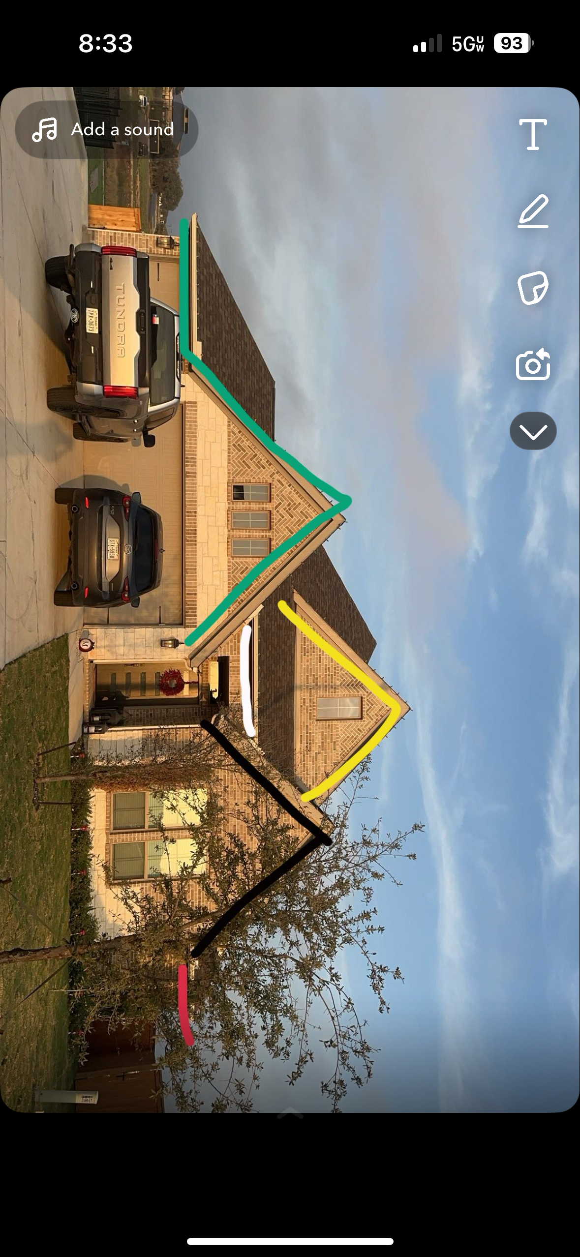 A house with a green and yellow roof with cars in the driveway against a blue sky.