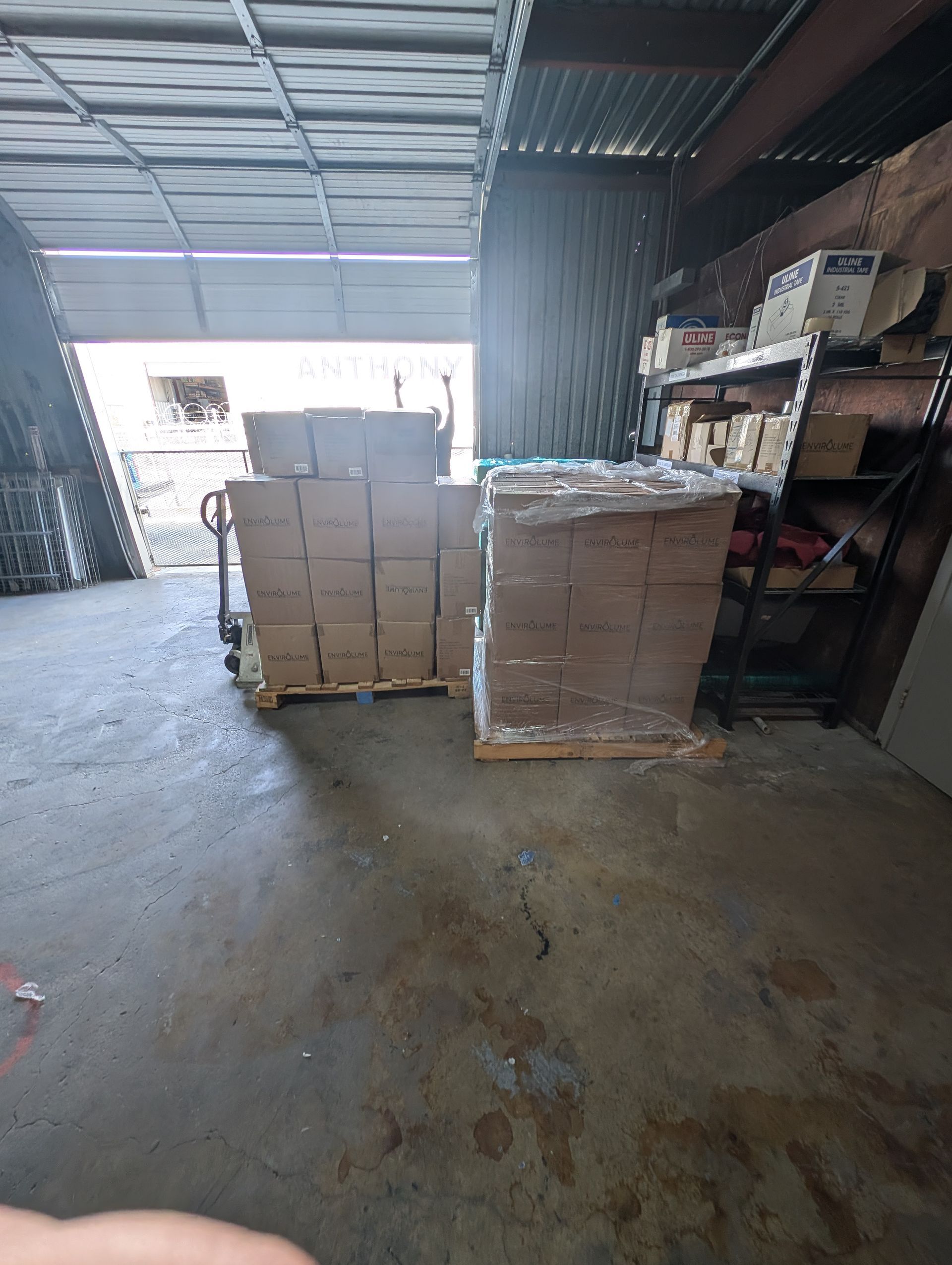 Warehouse interior with stacked cardboard boxes on pallets near a loading bay.