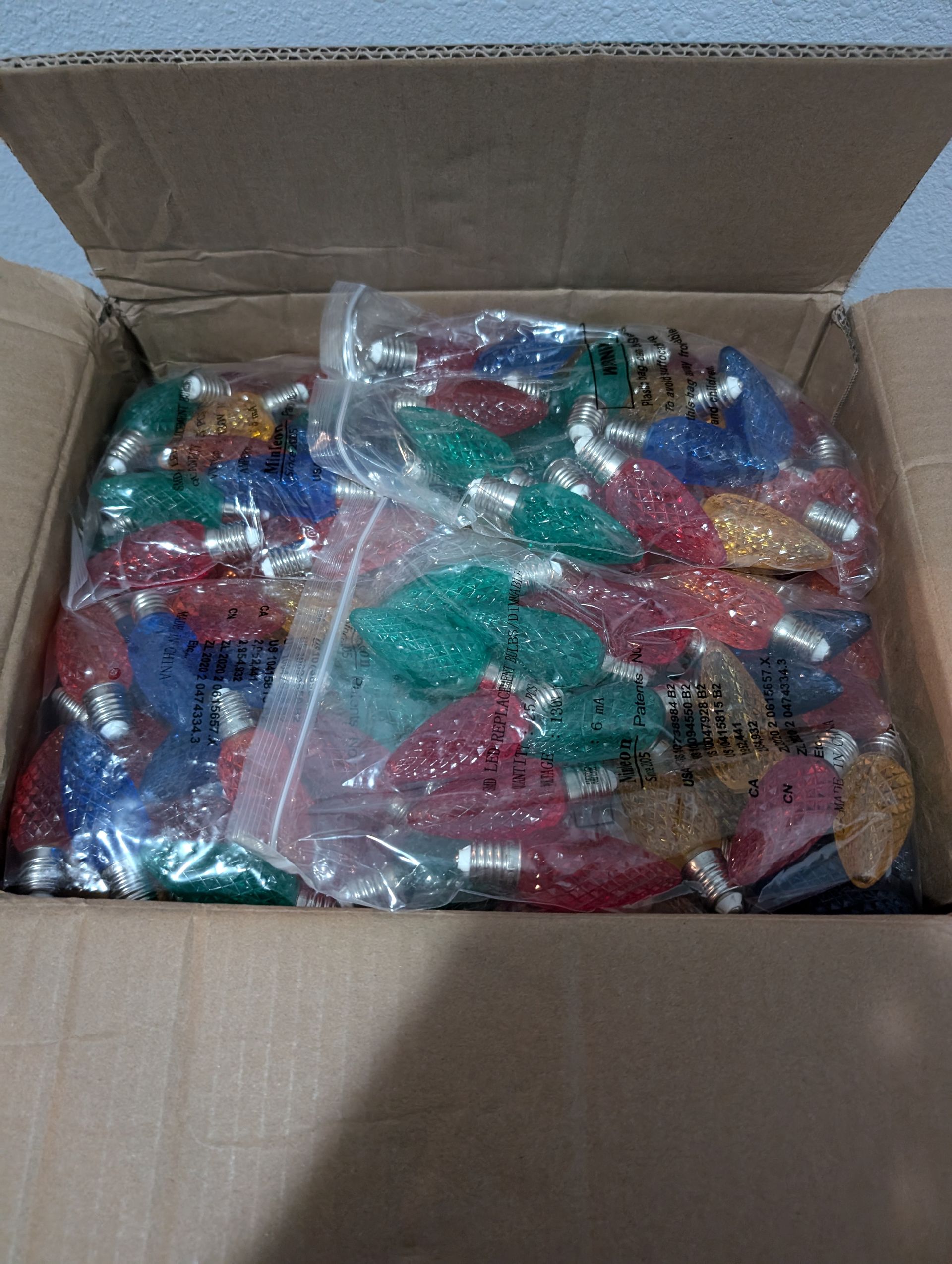Box filled with colorful Christmas tree light bulbs in plastic bags.