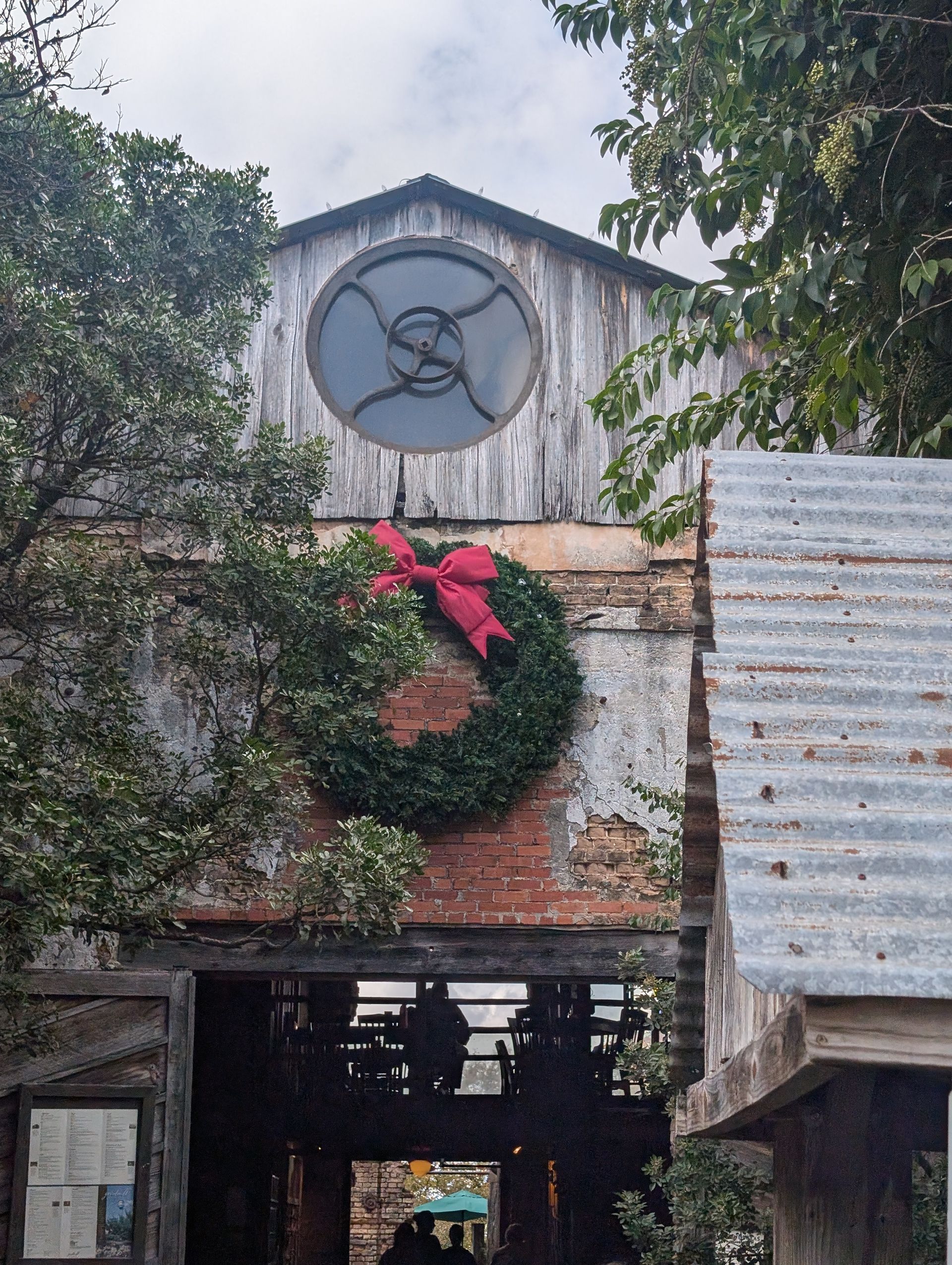 Old brick building with a green wreath and red bow. A round window is at the top.