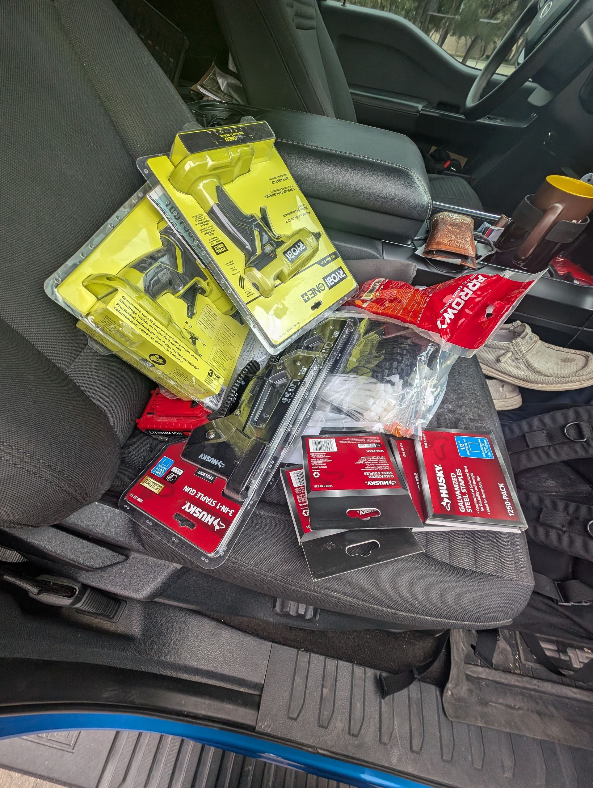 Items, including yellow tools and red boxes, on a vehicle's gray seat.