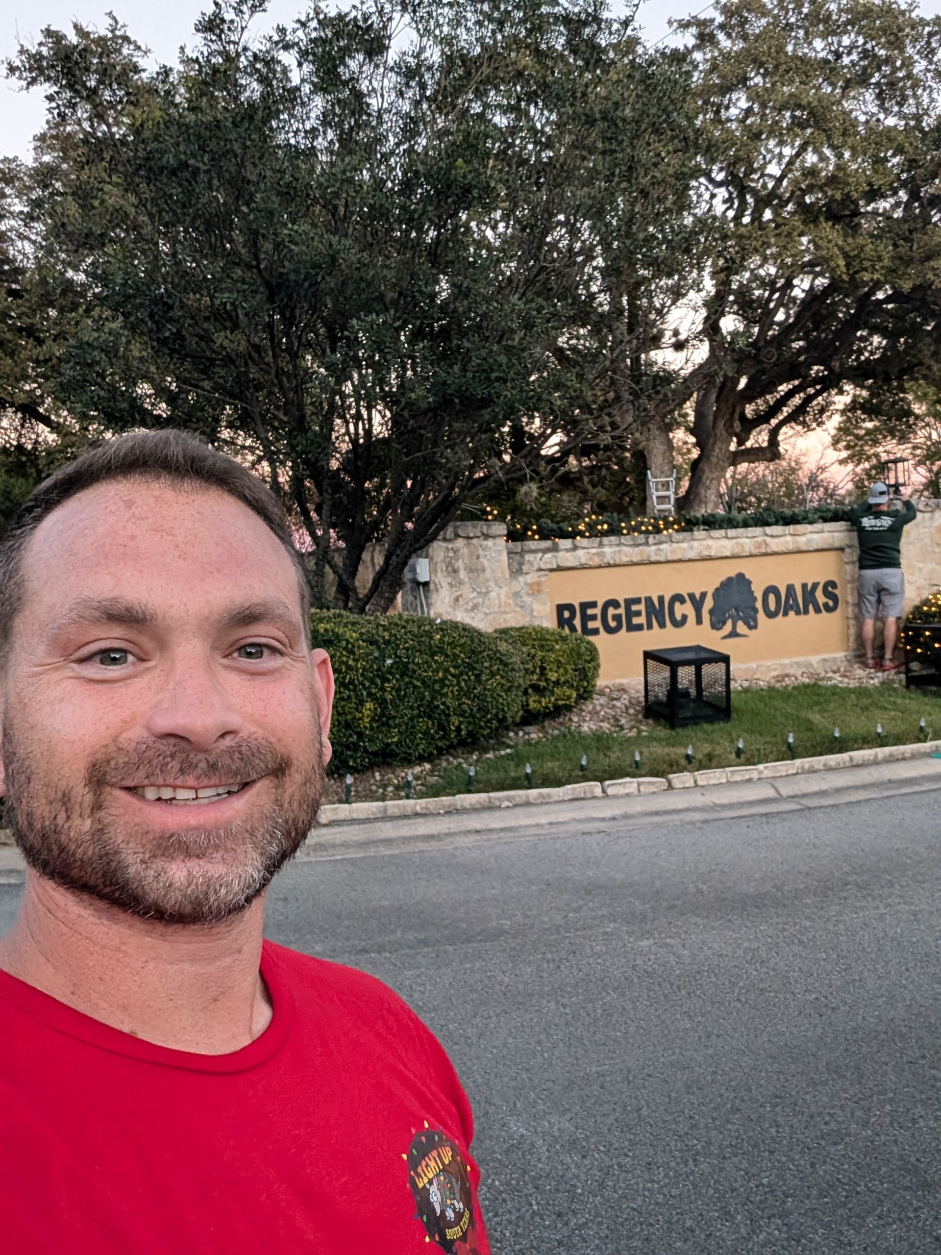 Man in red shirt smiles in front of 