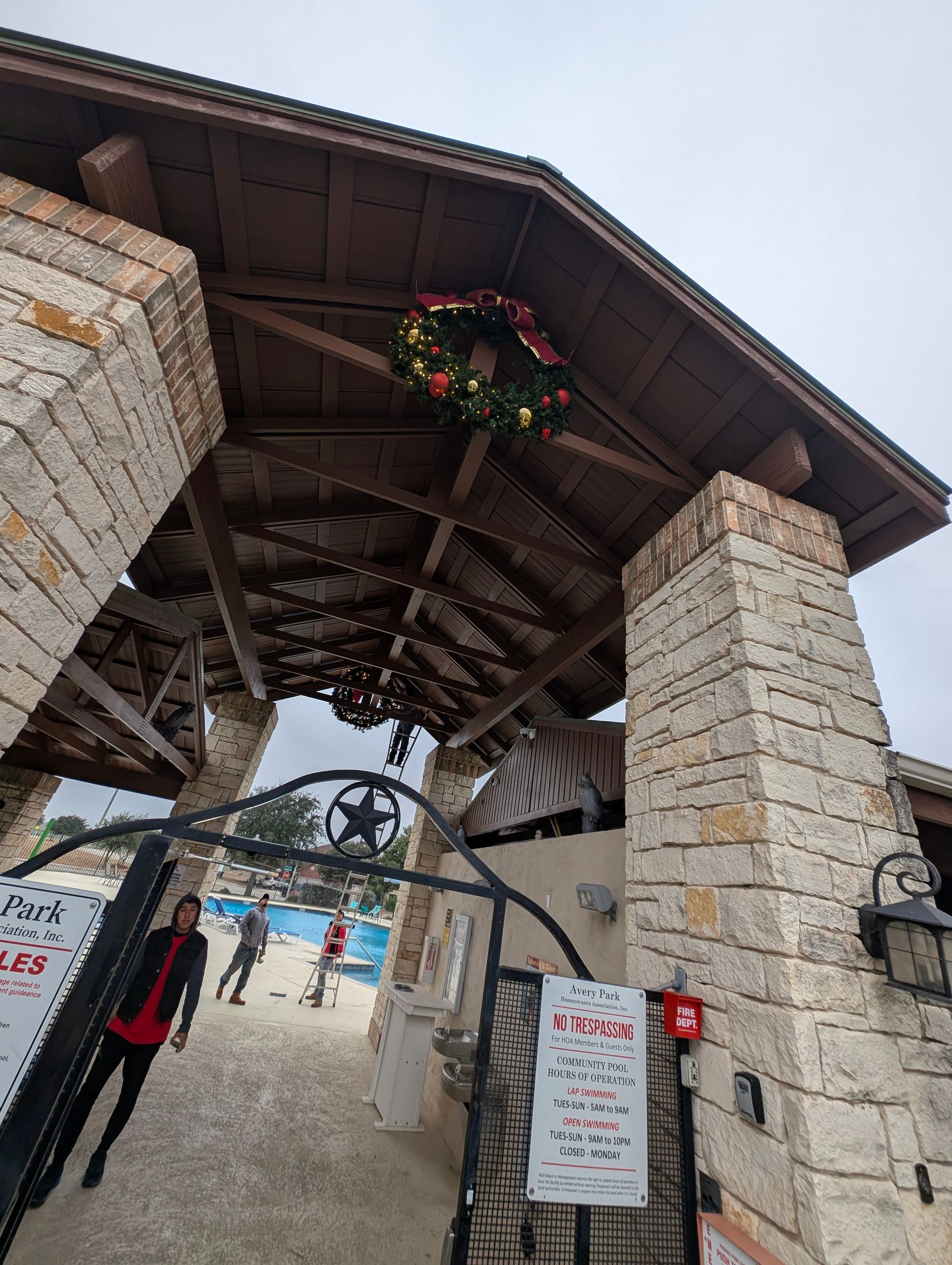 Entrance to a building with stone columns and a wooden roof, adorned with a Christmas wreath.
