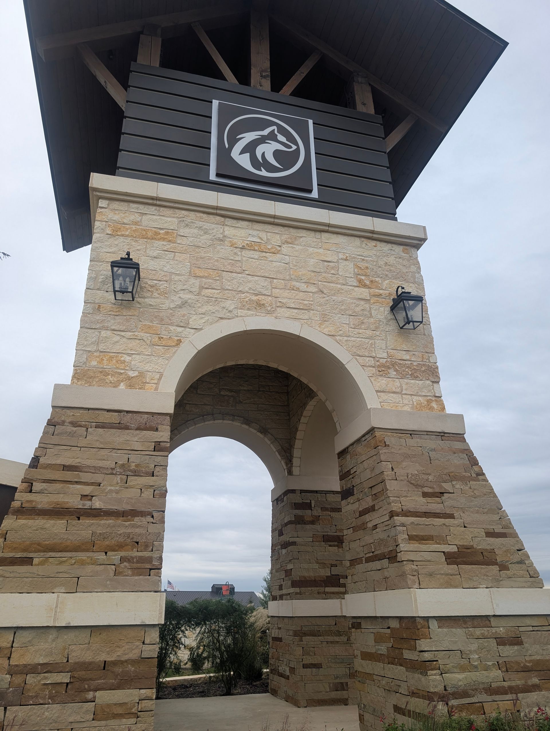 Stone archway with a logo of a wolf with a decorative top.