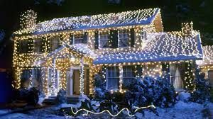 House covered in white Christmas lights, surrounded by snow.