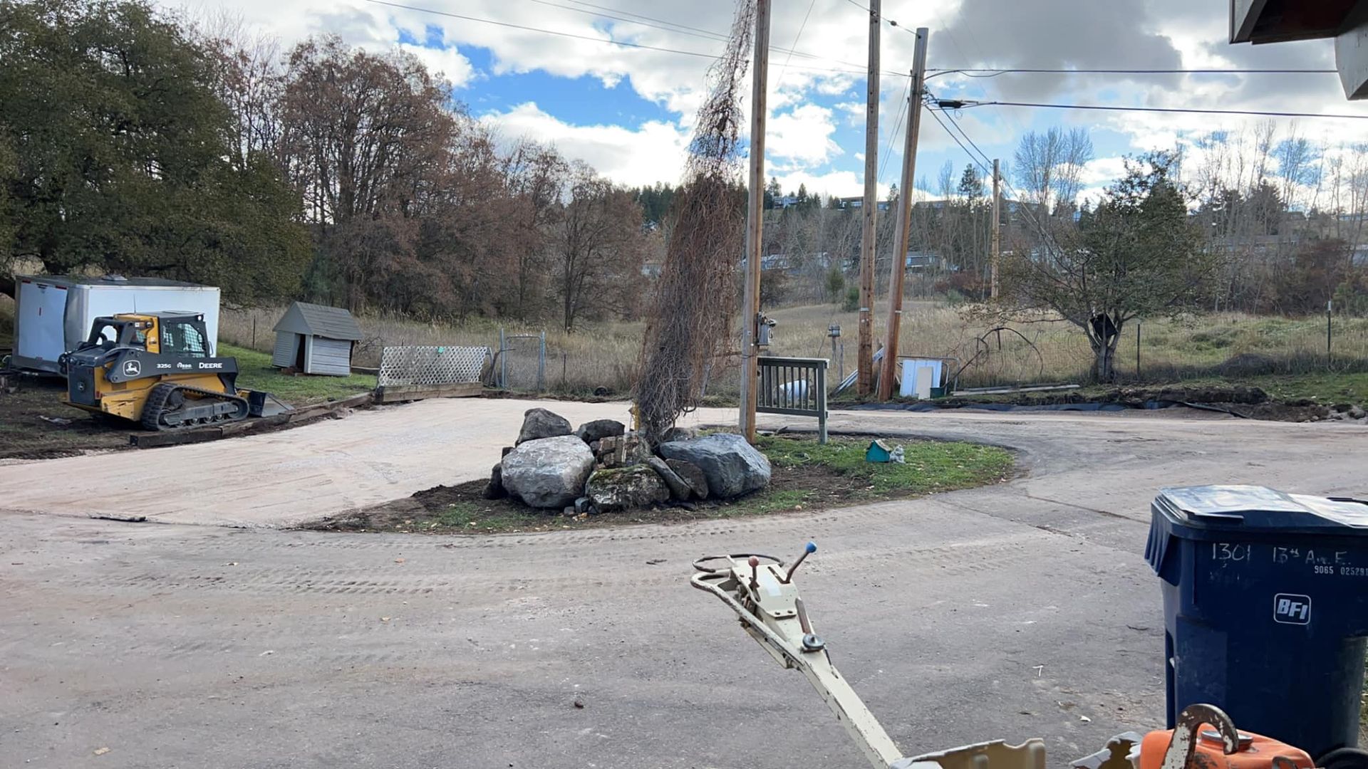 A tractor is parked in a parking lot next to a trash can.