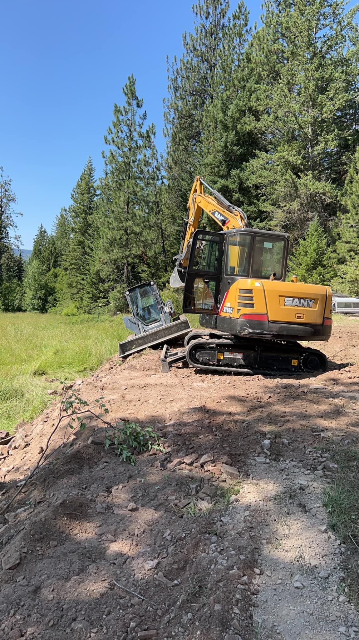 A yellow excavator is sitting on top of a dirt field.