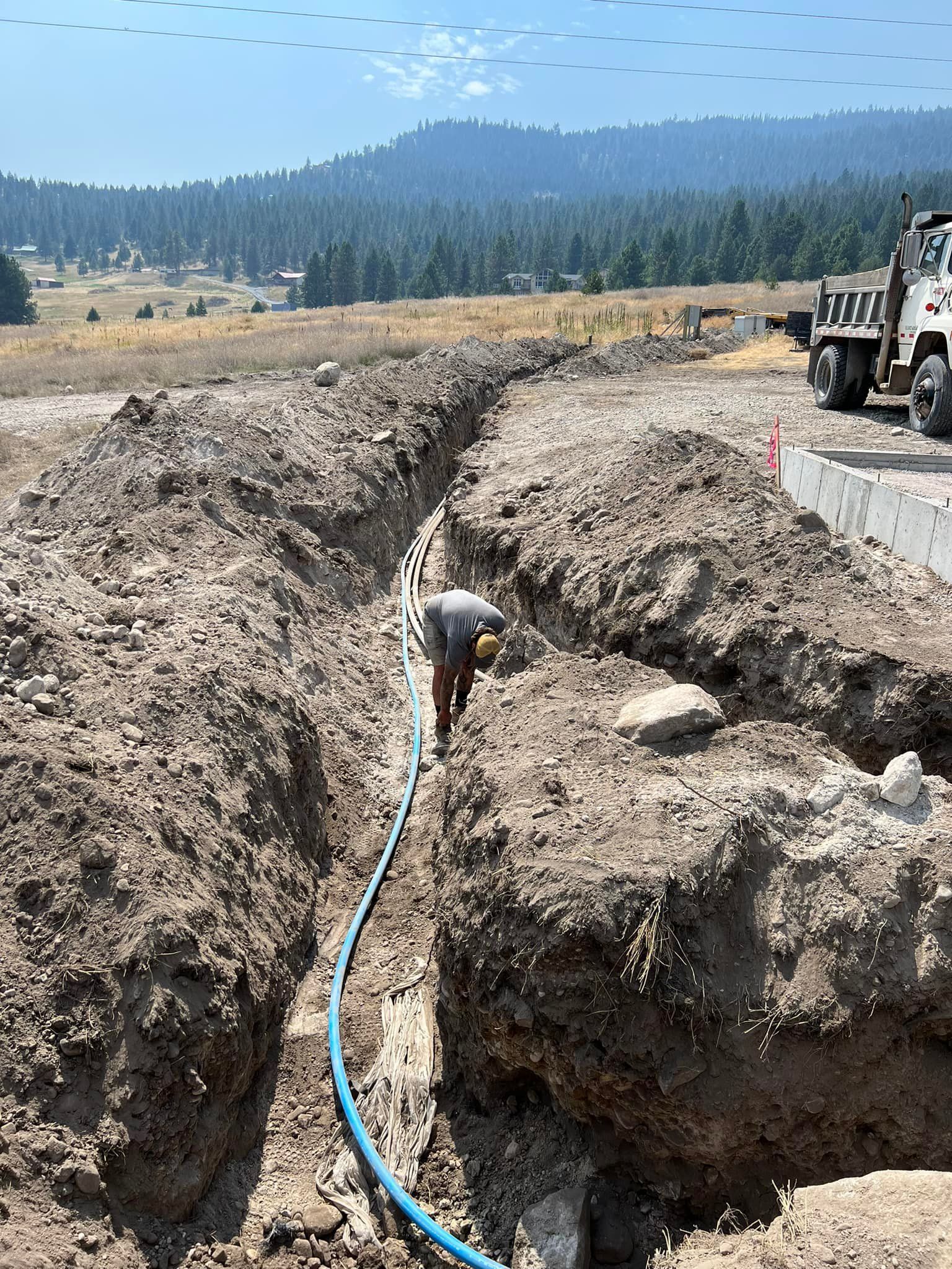 A man is digging a hole in the dirt with a hose.