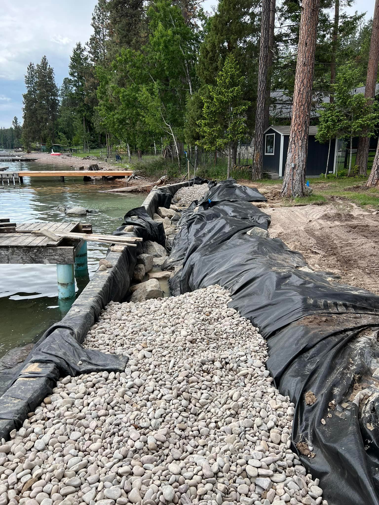 A pile of gravel is sitting next to a body of water.