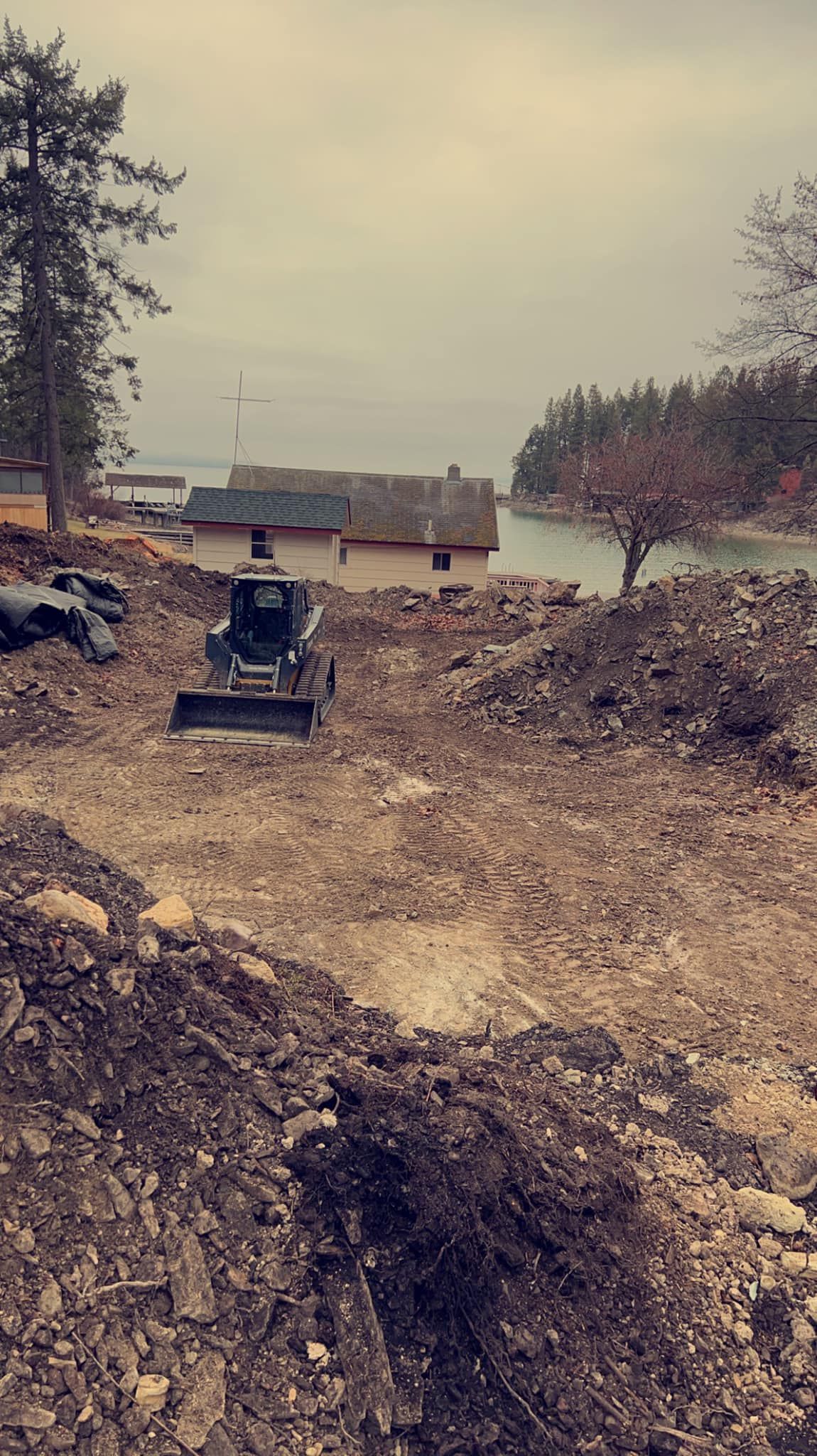 A bulldozer is moving dirt in a field with a house in the background.