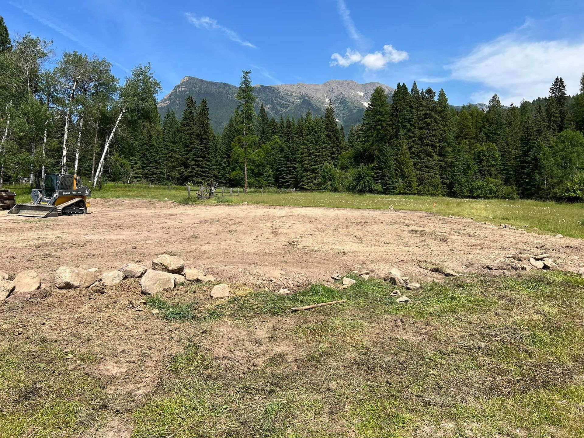There is a bulldozer in the middle of a field with trees in the background.