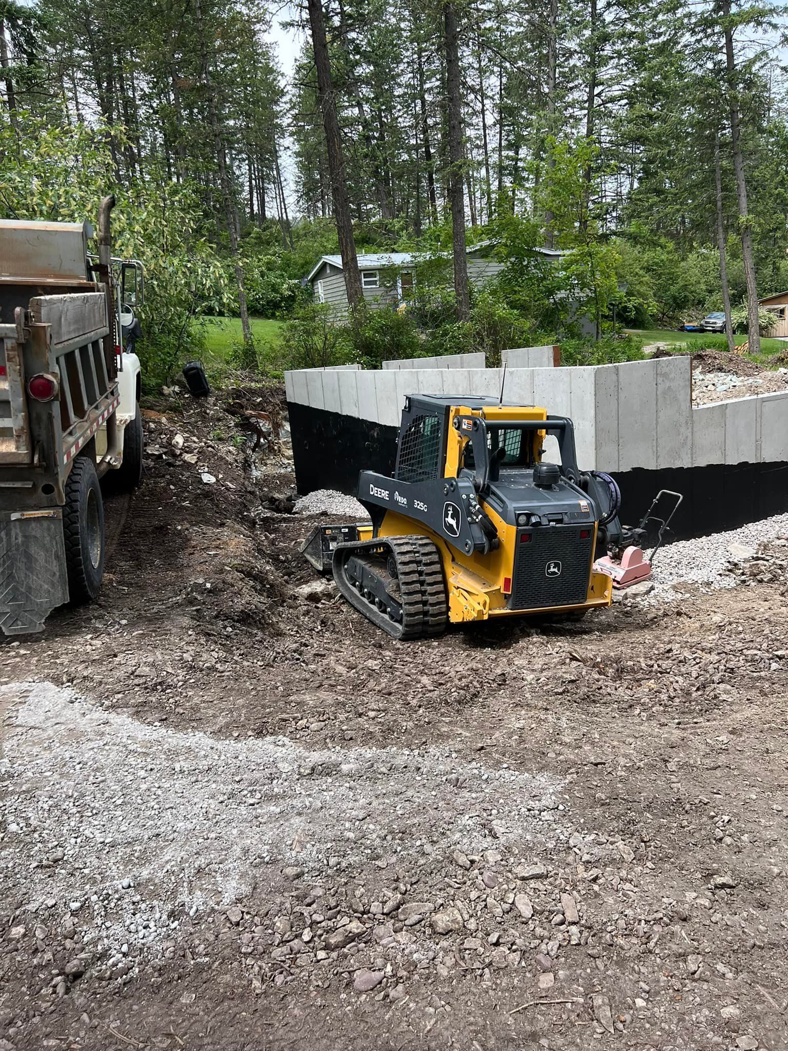 A bulldozer is driving down a dirt road next to a dump truck.