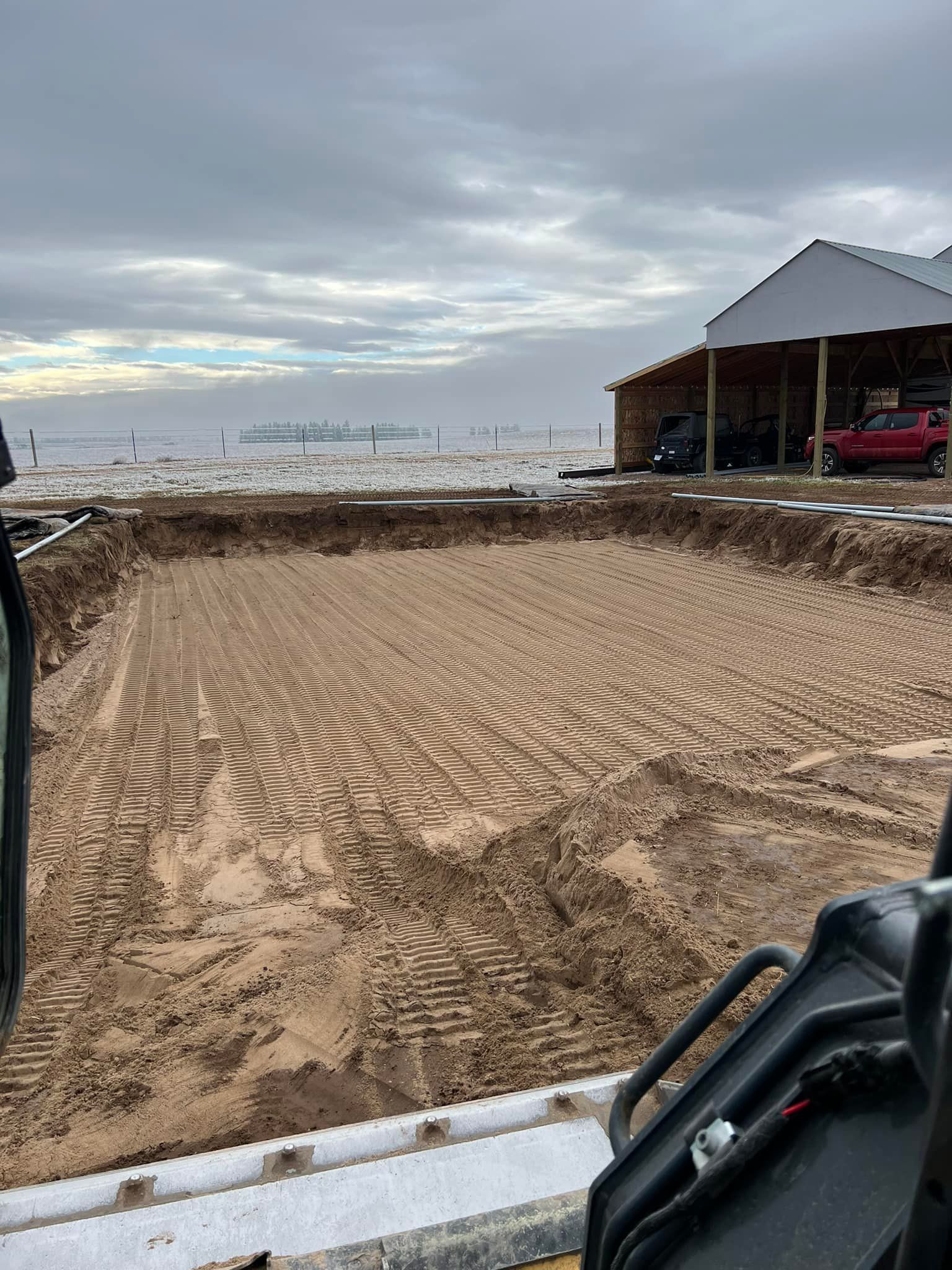 A tractor is digging a hole in the dirt in front of a building.